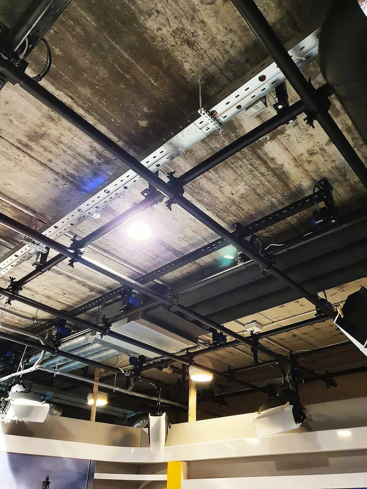 Ceiling with exposed pipes and lighting fixtures in an industrial-style space.