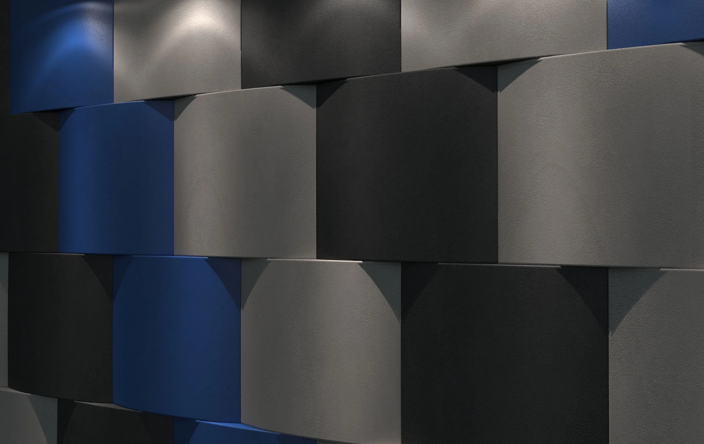Close-up of a modern, textured wall composed of rectangular tiles in black, gray, and blue, with shadows cast on the tiles.