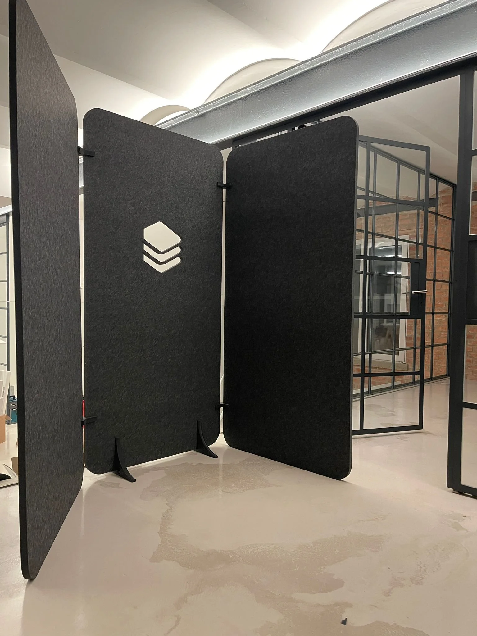 Modern black and gray display boards and a metal grid display structure in an indoor setting with brick walls and windows in the background.