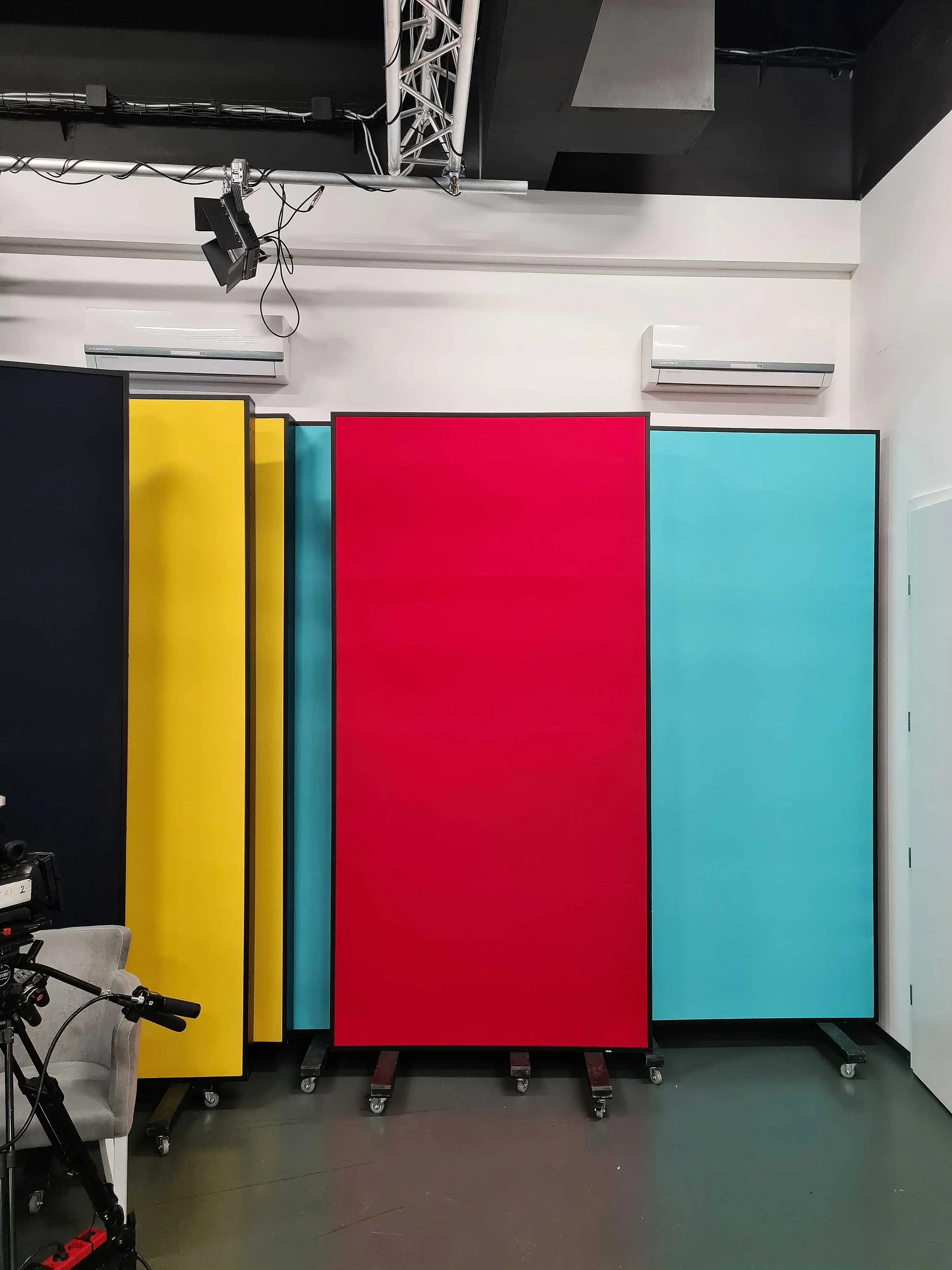 Colorful mobile room dividers in yellow, red, and turquoise in a studio or office space.