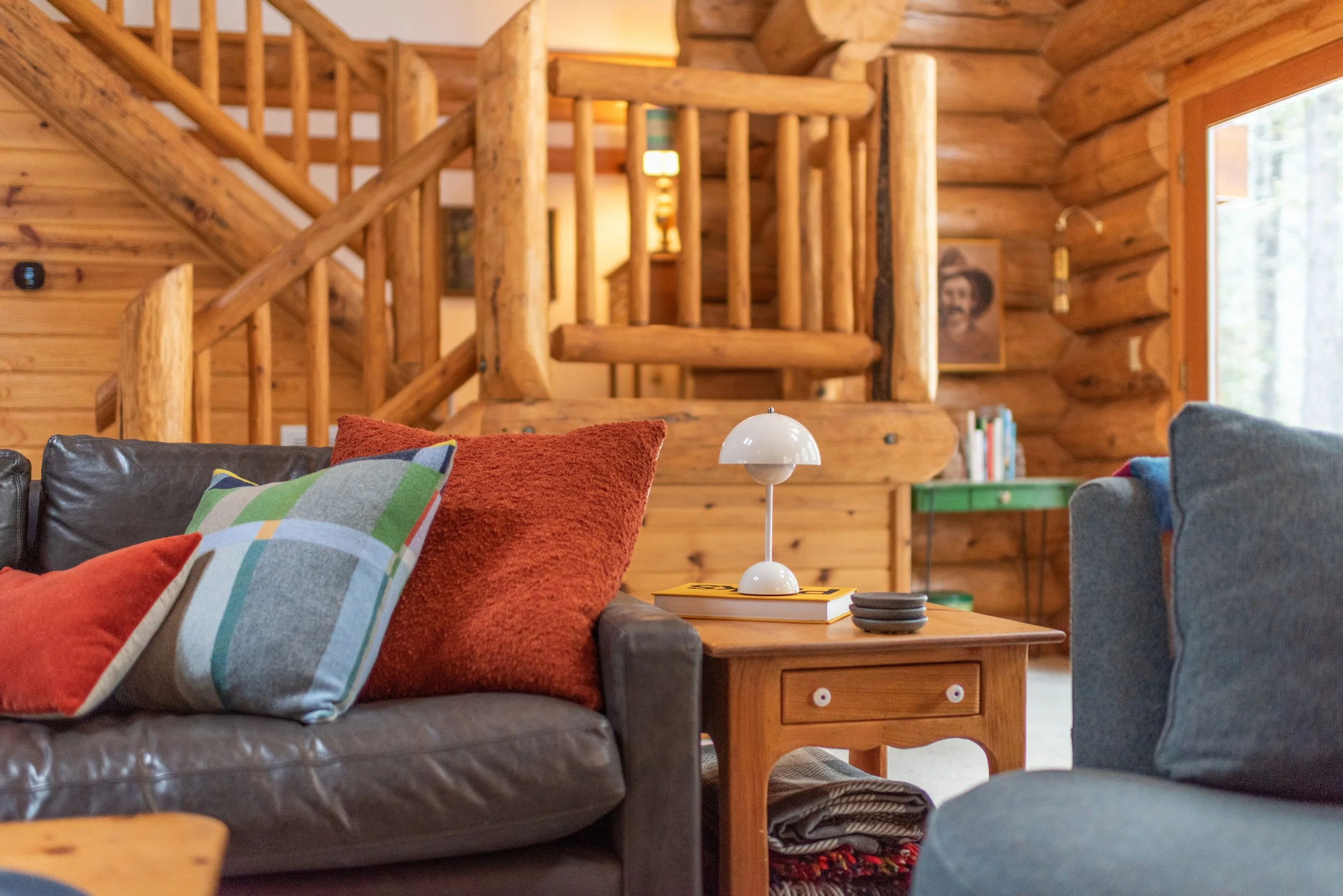 In the living room, we decided to go with a brown leather sofa that will last a lifetime! We paired it with modern accent pillows and a cordless lamp since no outlets are close by and the cabin is dark.