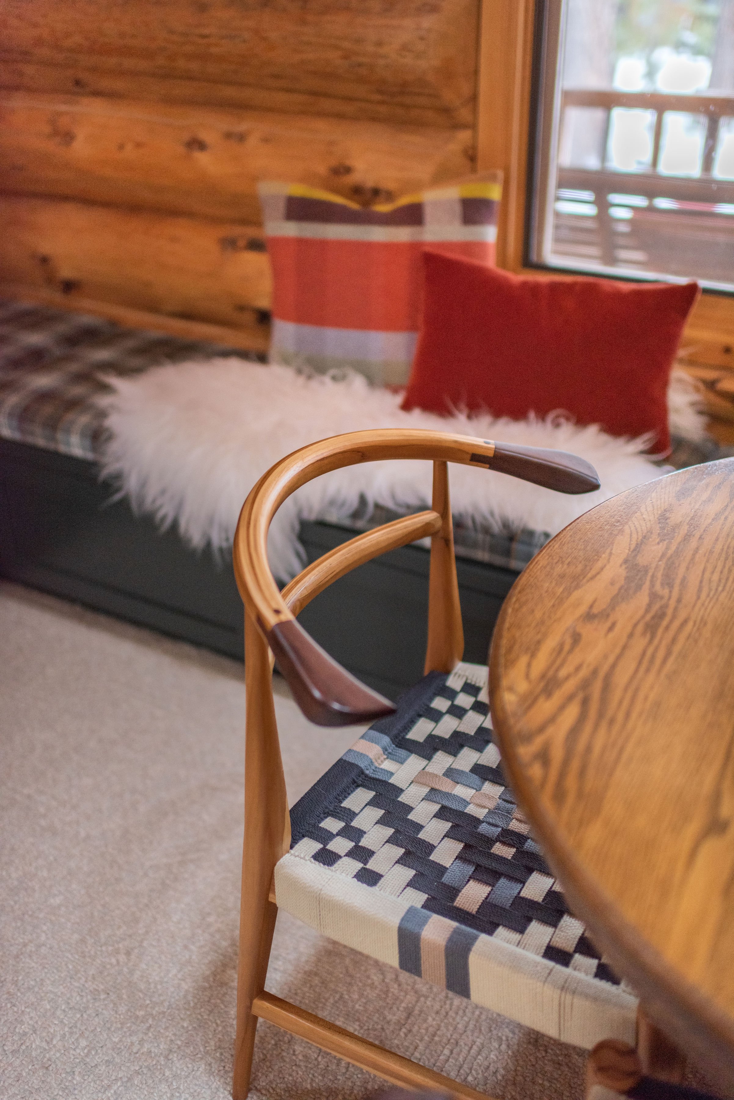 The cabin game table (also used for arts & crafts for the kids) features woven chairs from Anthropologie, textured pillows, and a cozy fur throw blanket.