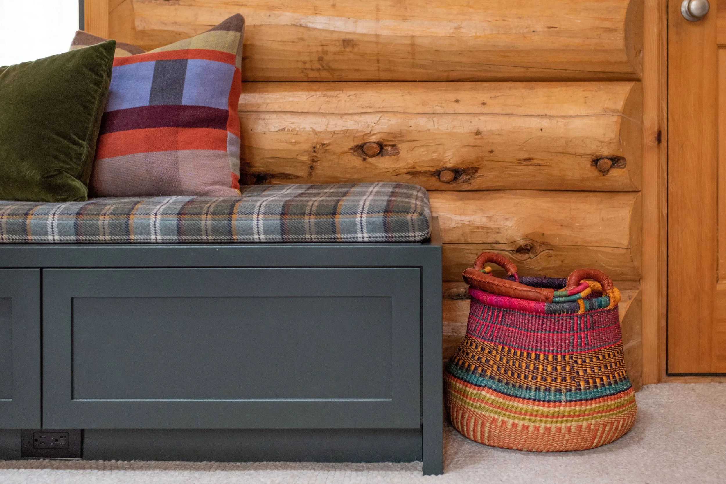 This custom built-in painted "Green Essex" by Benjamin Moore takes a traditional home and modernizes it. The Pendleton fabric upholstery and modern pillows paired with a bright colored woven basket for shoes, makes for a great entry moment into the l