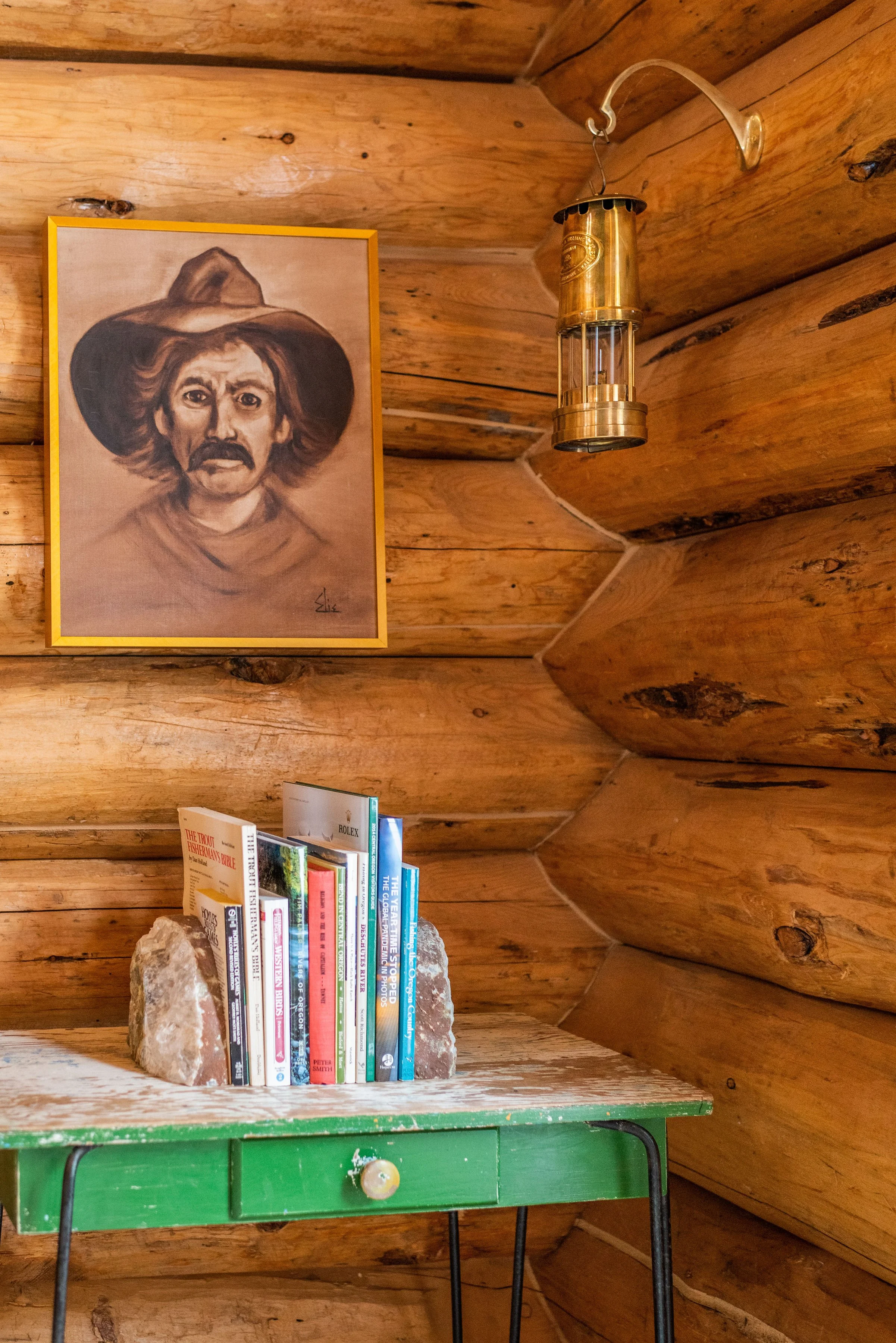 This corner cabin moment by the back door features a green vintage table, art from a local thift shop, and a beautiful metal lantern.