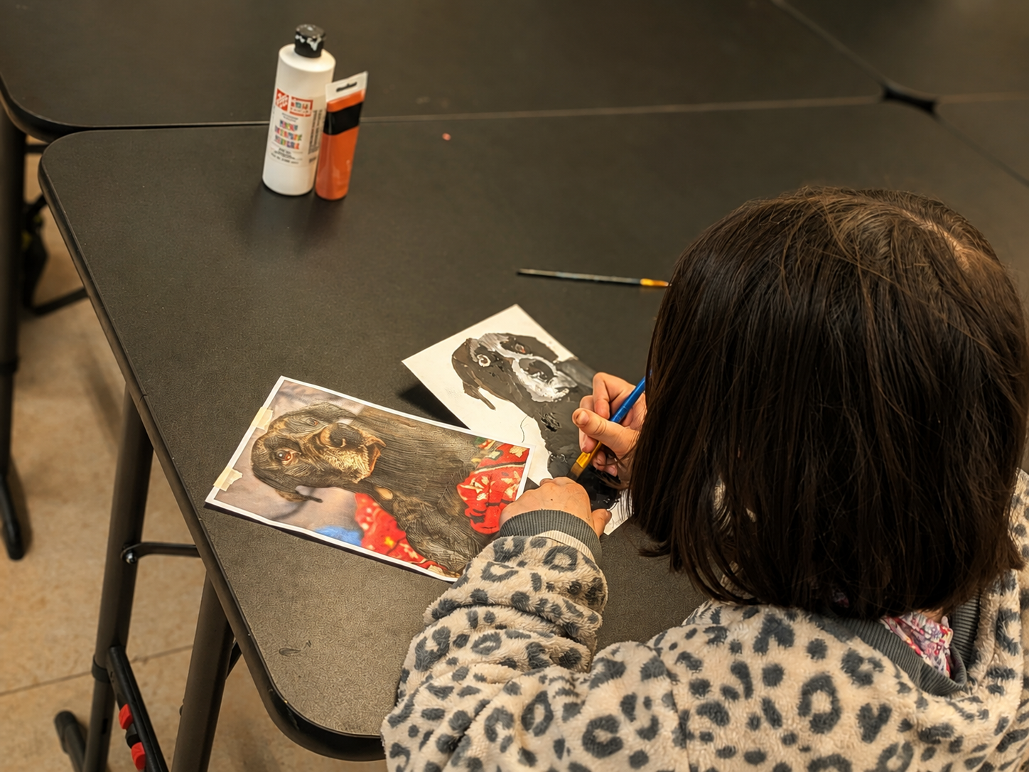 Student painting a dog from reference photos at Paint Away Art Studio