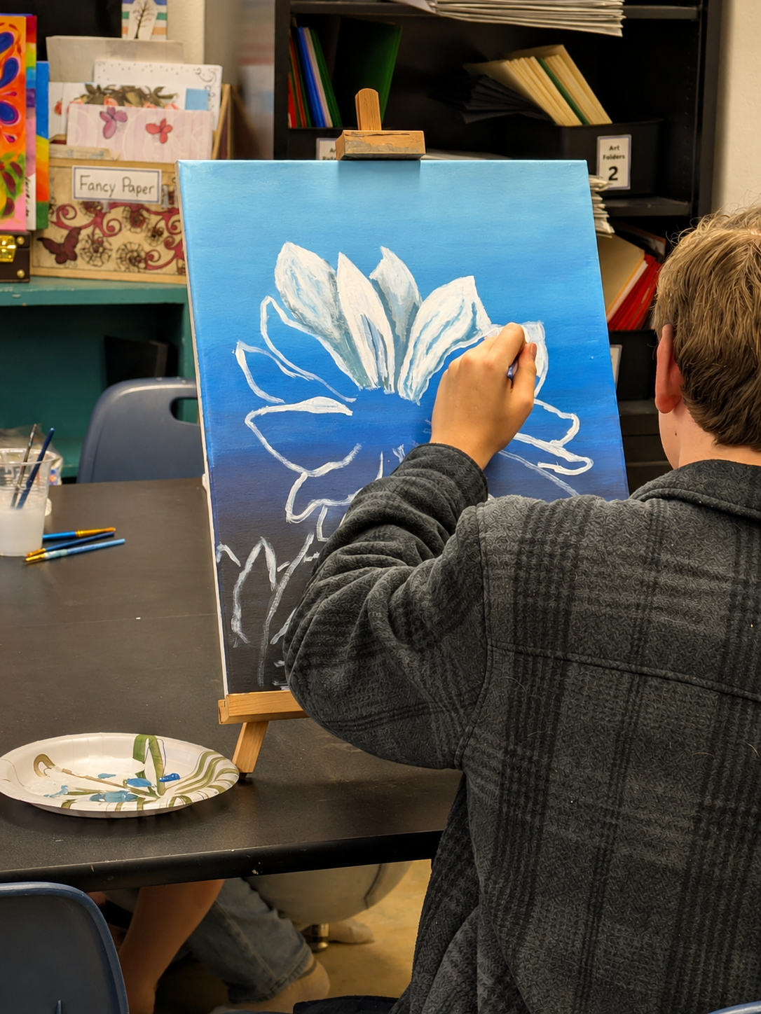 High school Student painting a blue-and-white flower during an art class at Paint Away Art Studio