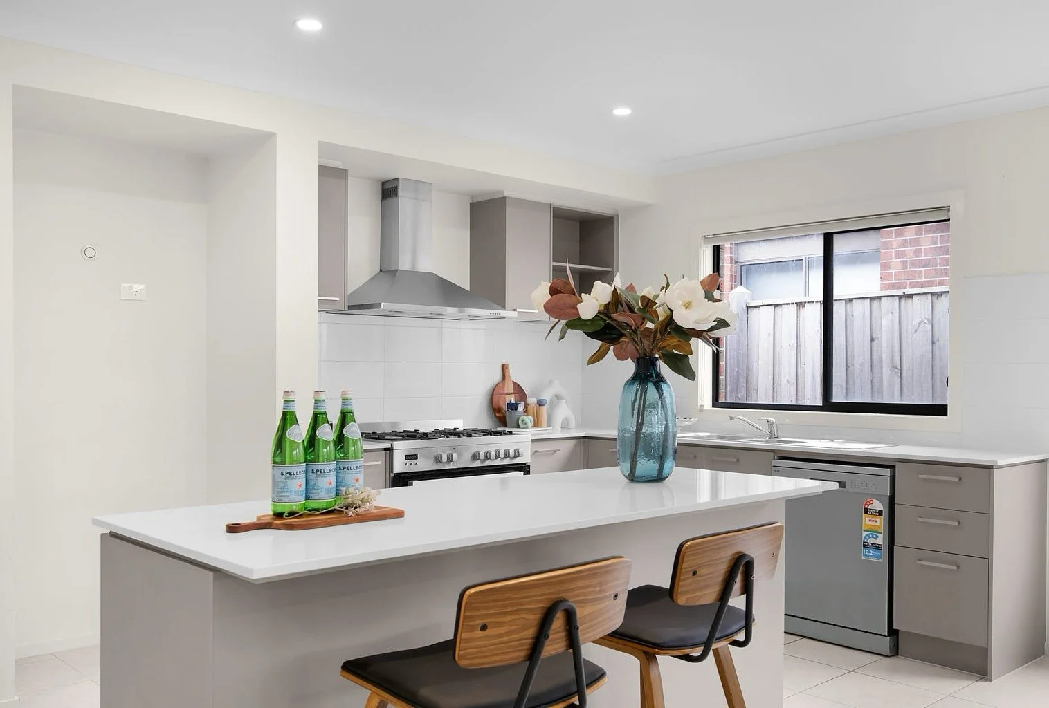 Modern dining room with a table, yellow and dark chairs, an amber glass vase with branches, gold pendant lights, and blue curtains.