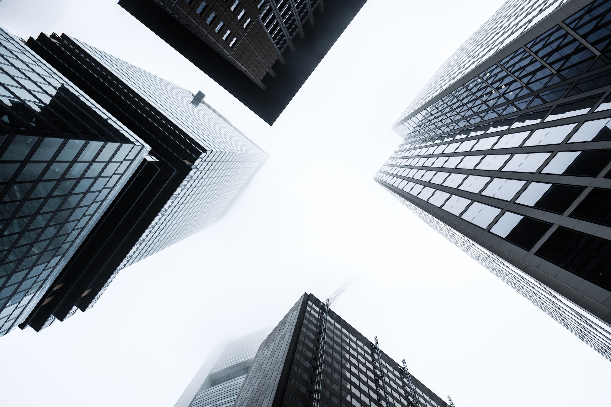 View of tall modern office buildings seen from below, looking up towards the cloudy sky.