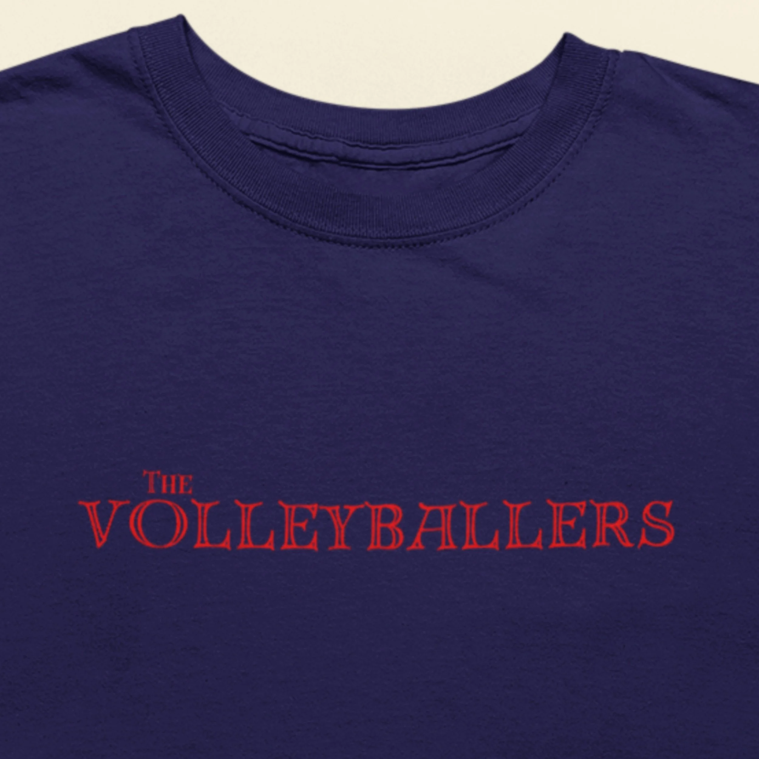 Navy blue shirt with 'The Volleyballers' text in red on a beige background.