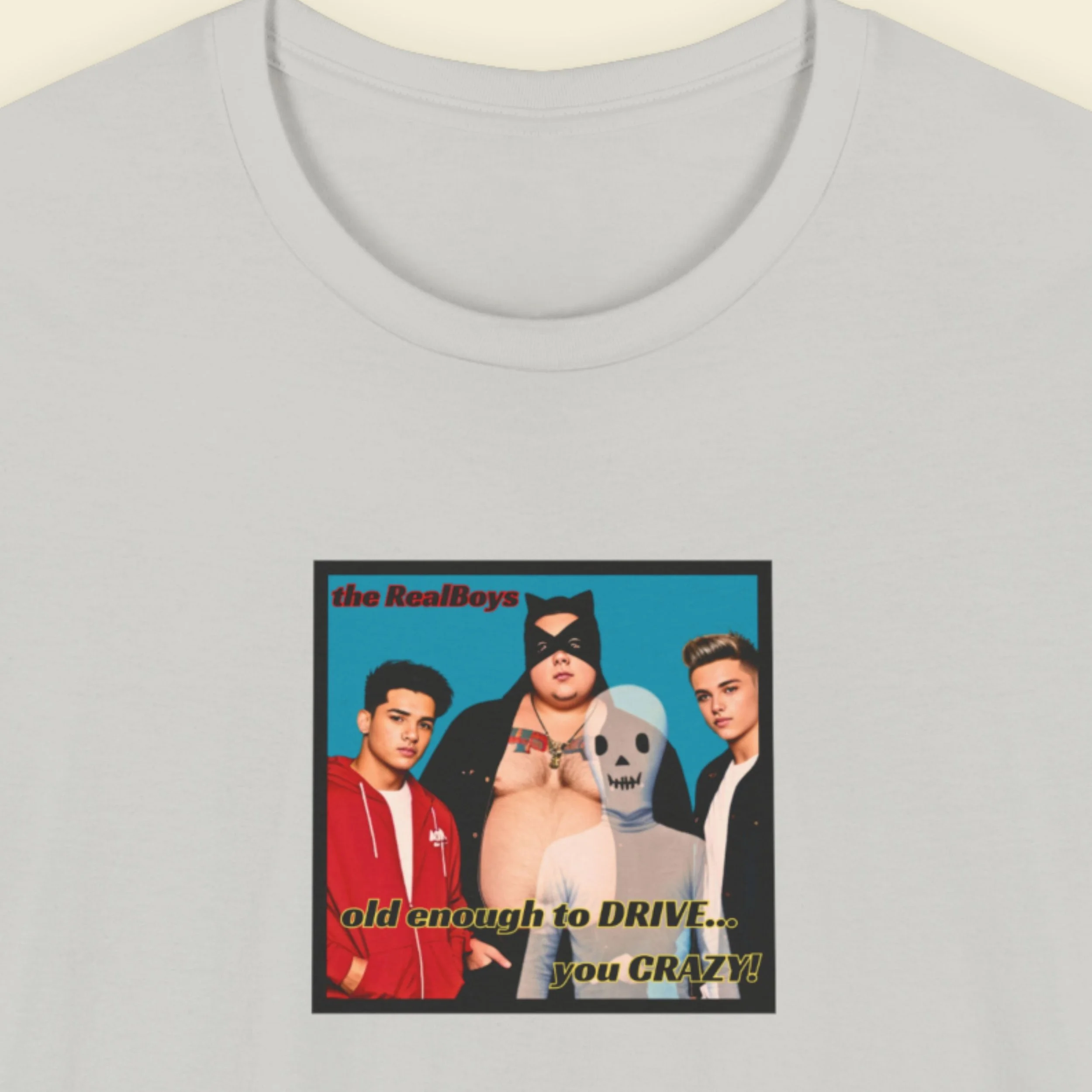 A closeup image of a light grey t-shirt featurng an album cover from the boy band the RealBoys, the title of the album is 'Old enough to drive you crazy.'