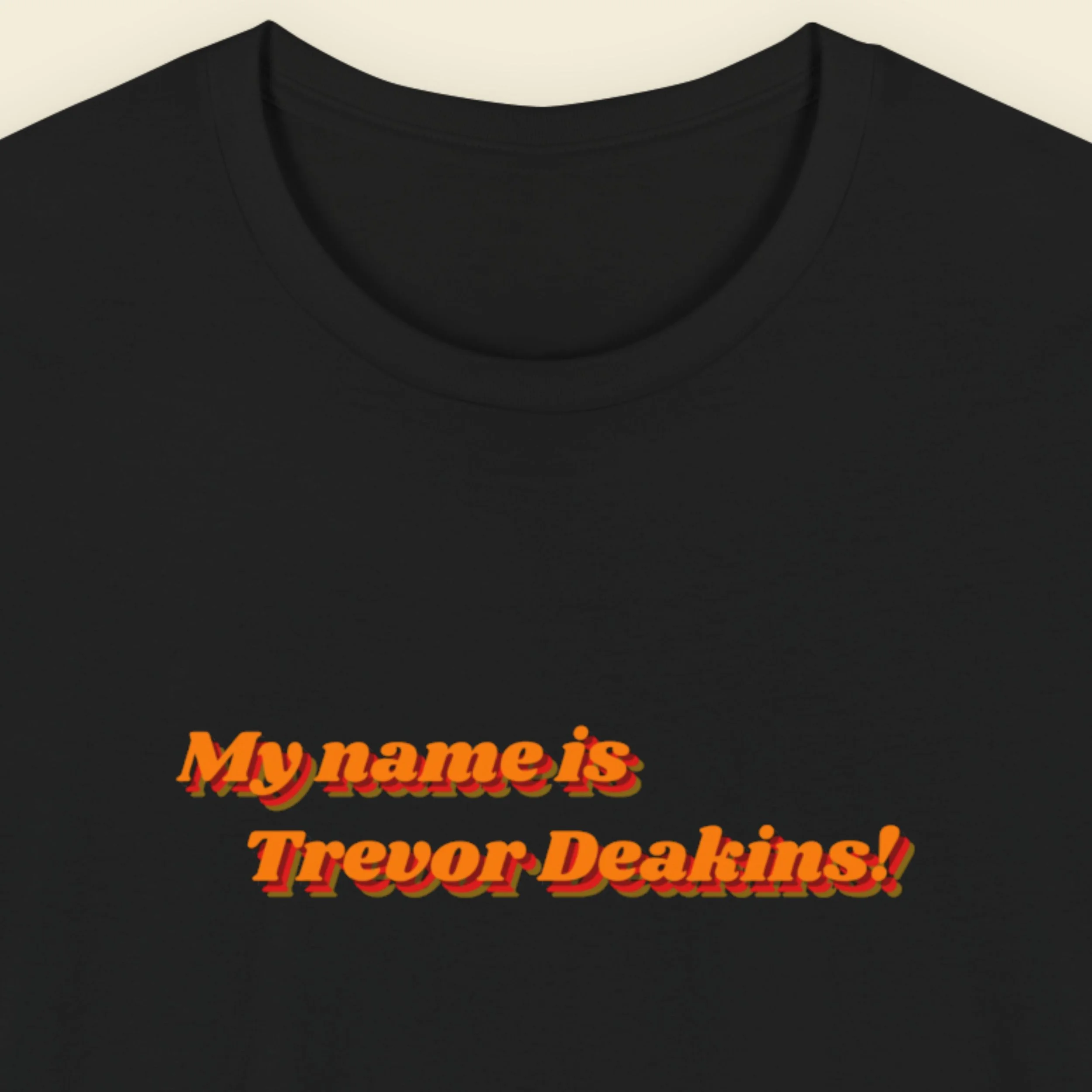 Black t-shirt with red text 'My name is Trevor Deakins!' on a beige background.