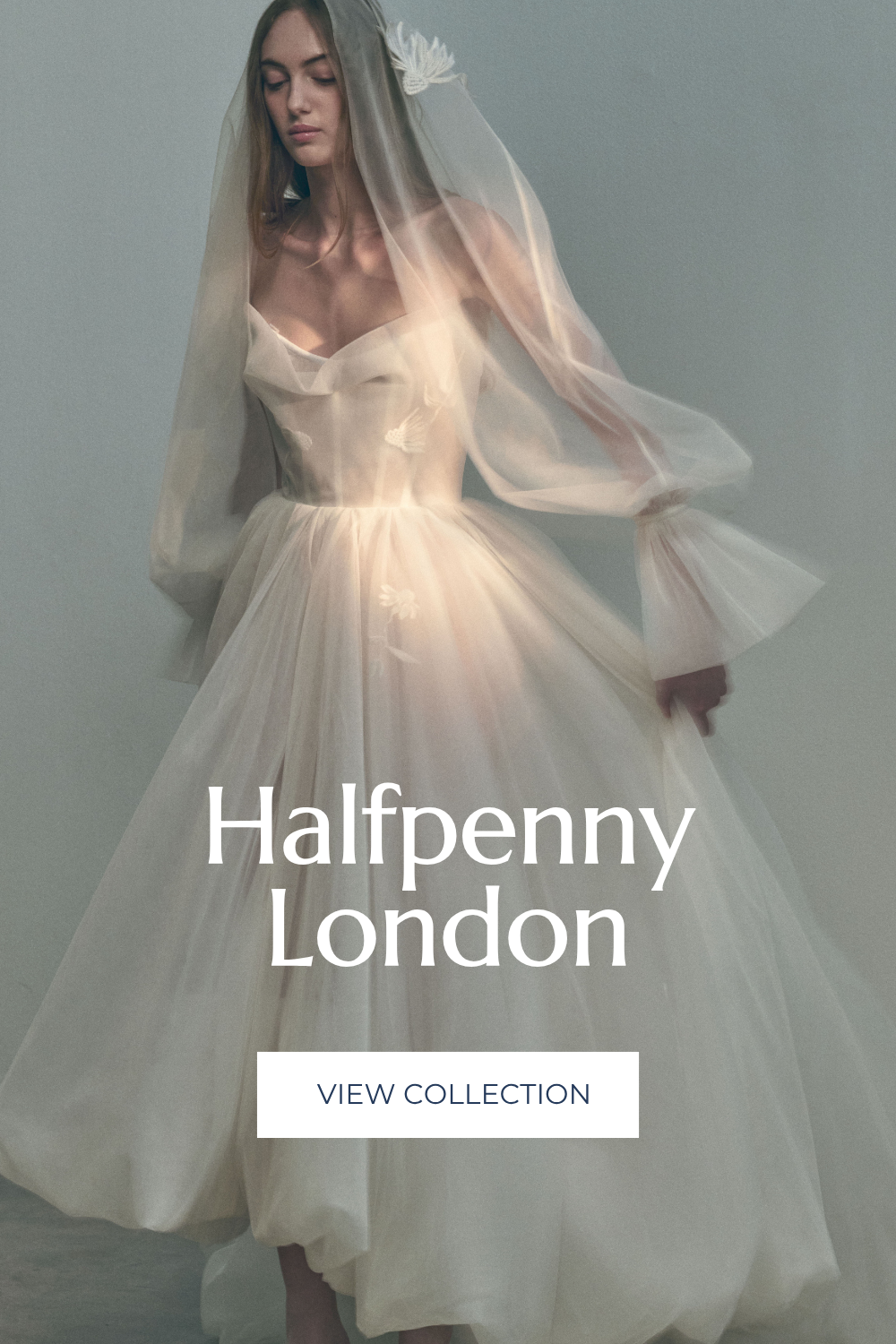A woman in a light, flowing wedding dress with a sheer veil. The dress has delicate white bird embroidery, and she has a calm, contemplative expression. The background is plain and neutral.