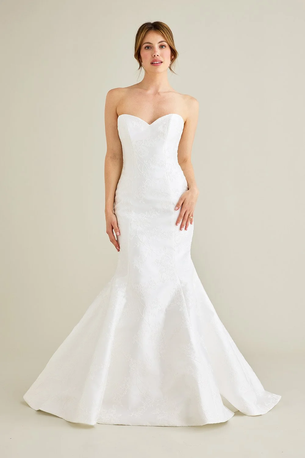 Lea-Ann Belter at New York Bridal Market  A woman in a strapless white wedding gown standing against a plain neutral background.