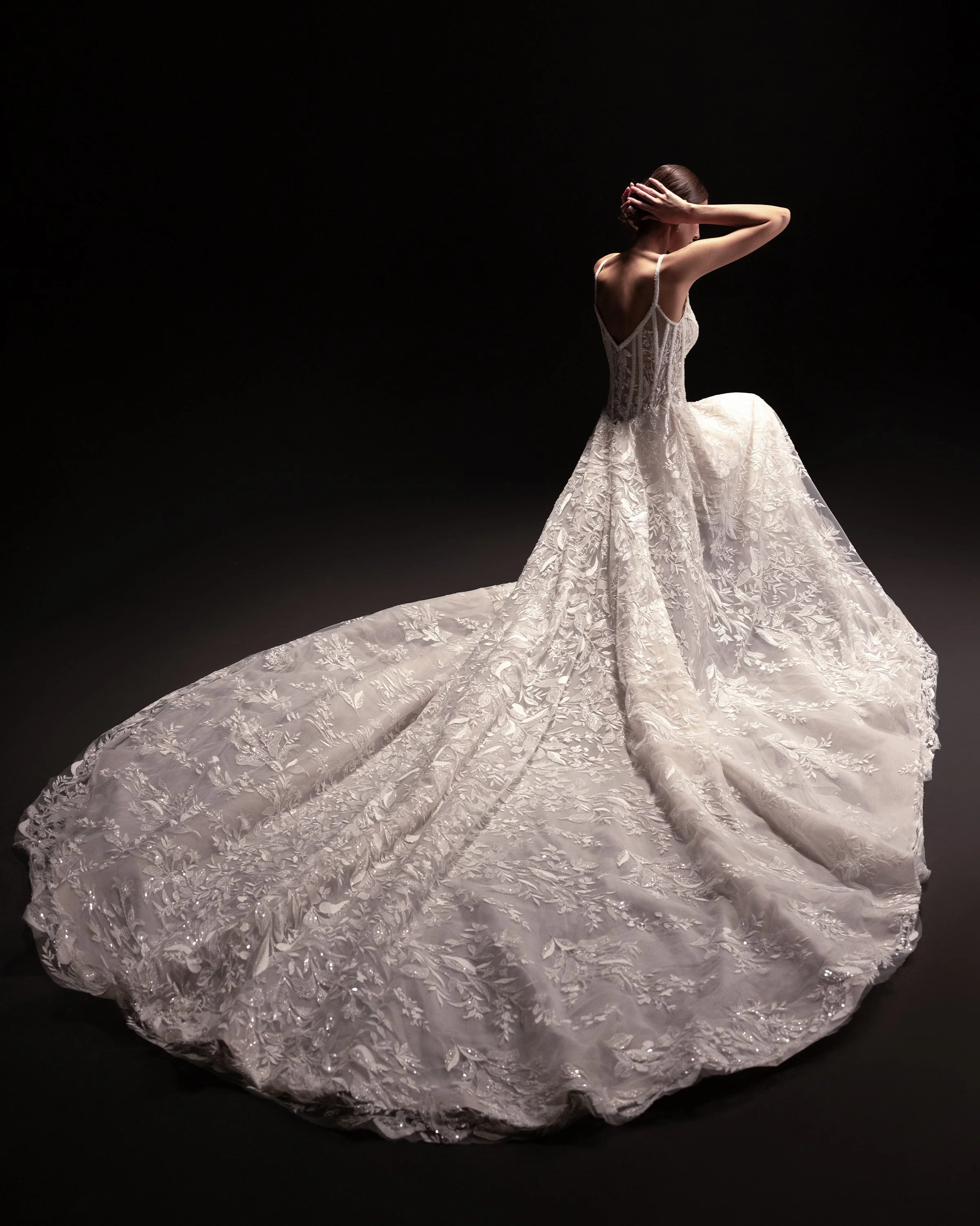 Gemy Maalouf at New York Bridal Makrket A woman in a wedding dress posing against a dark background.