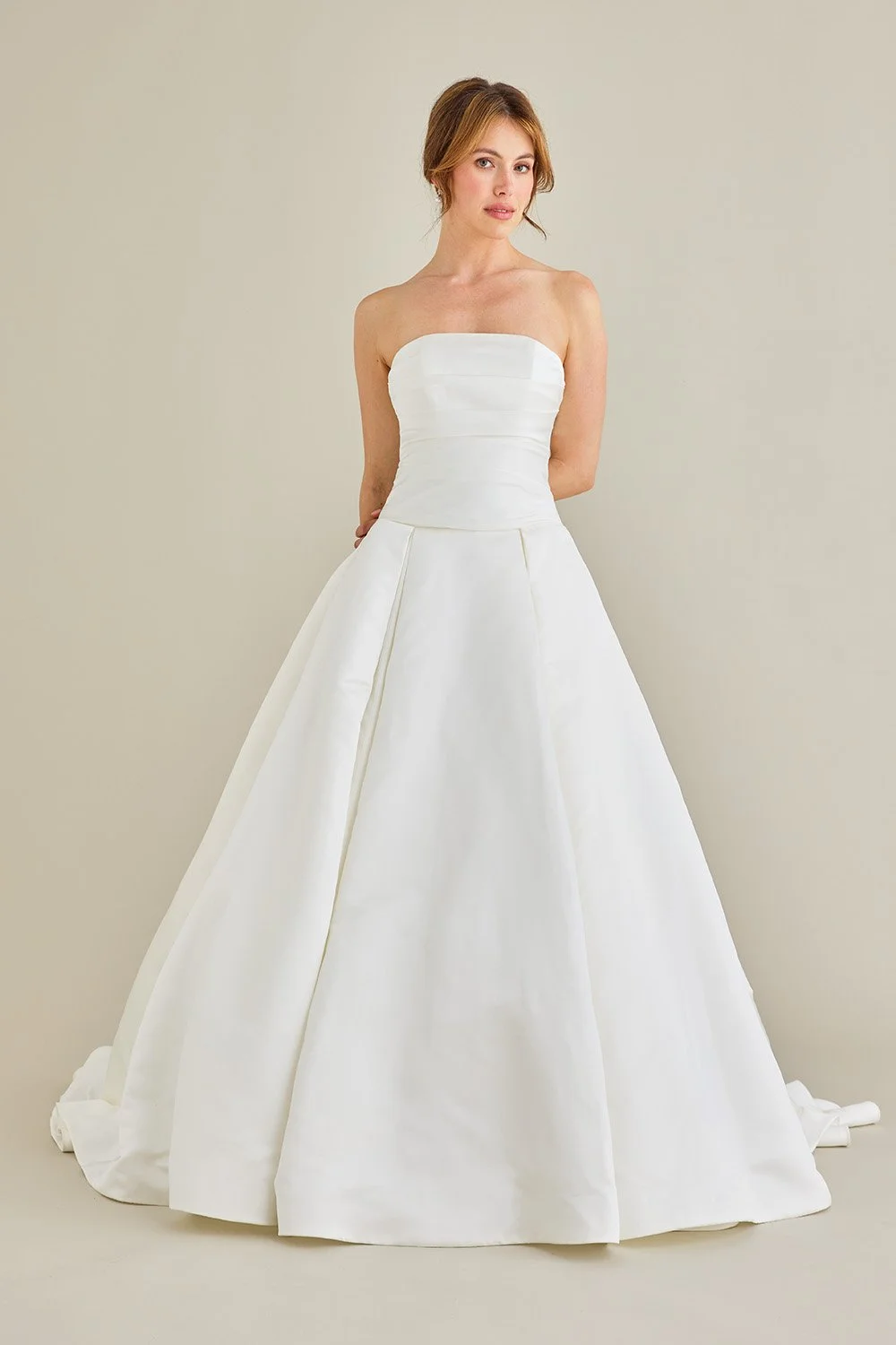 Lea-Ann Belter at New York Bridal Market A woman in a strapless white wedding gown standing against a plain background.