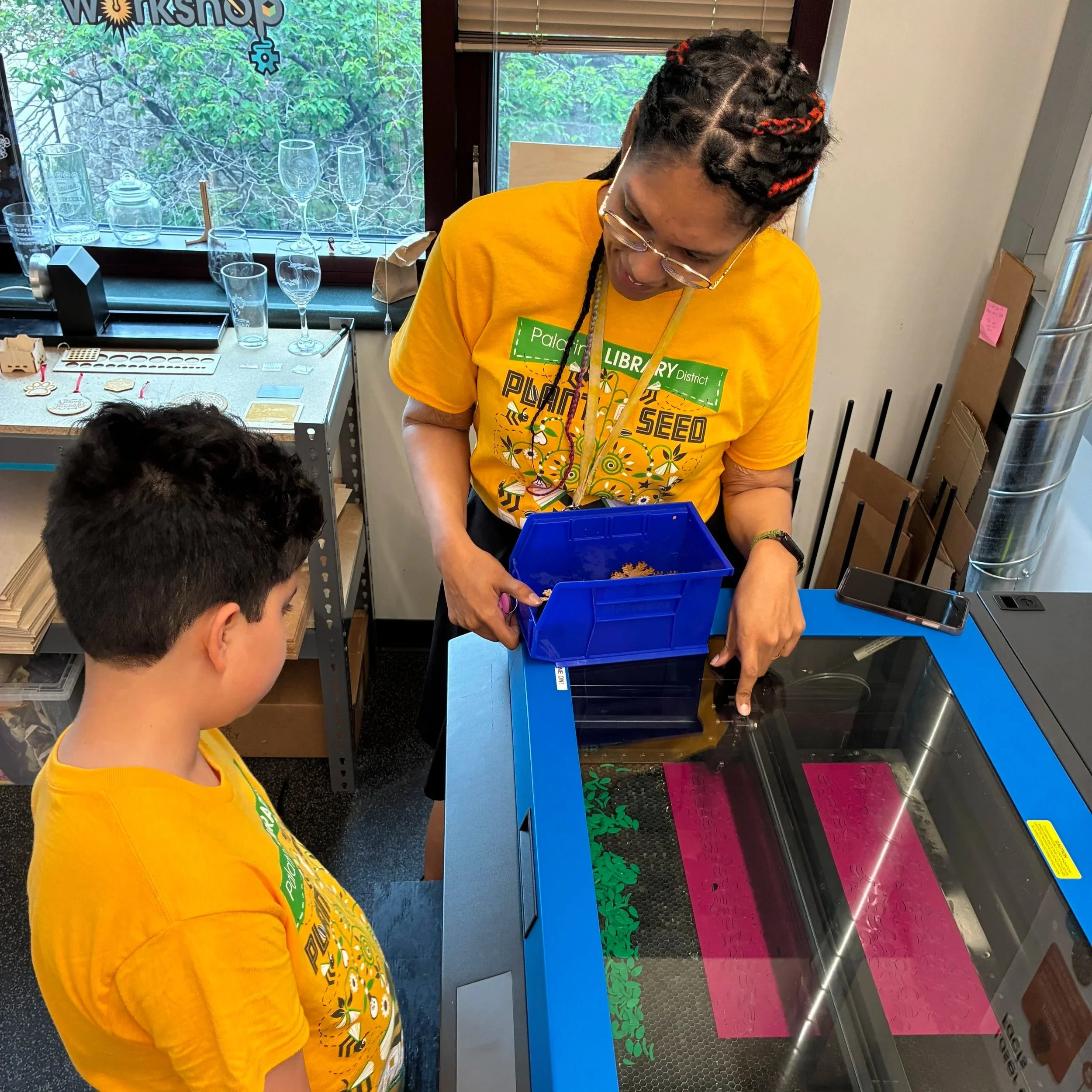 Teaching a child how a laser cutter works during a community makerspace program.