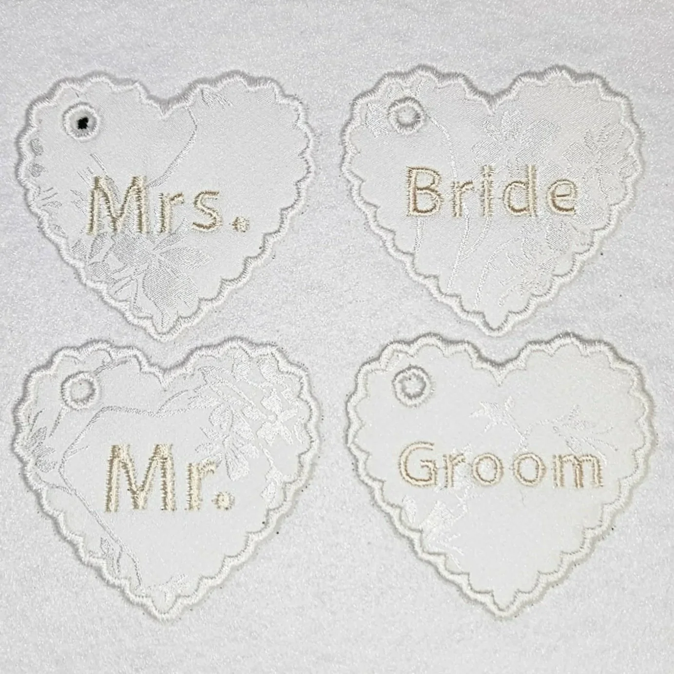 Personalized heart-shaped wedding charms with keychain holes, embroidered in rose gold thread, designed for brides, grooms, and wedding party keepsakes.