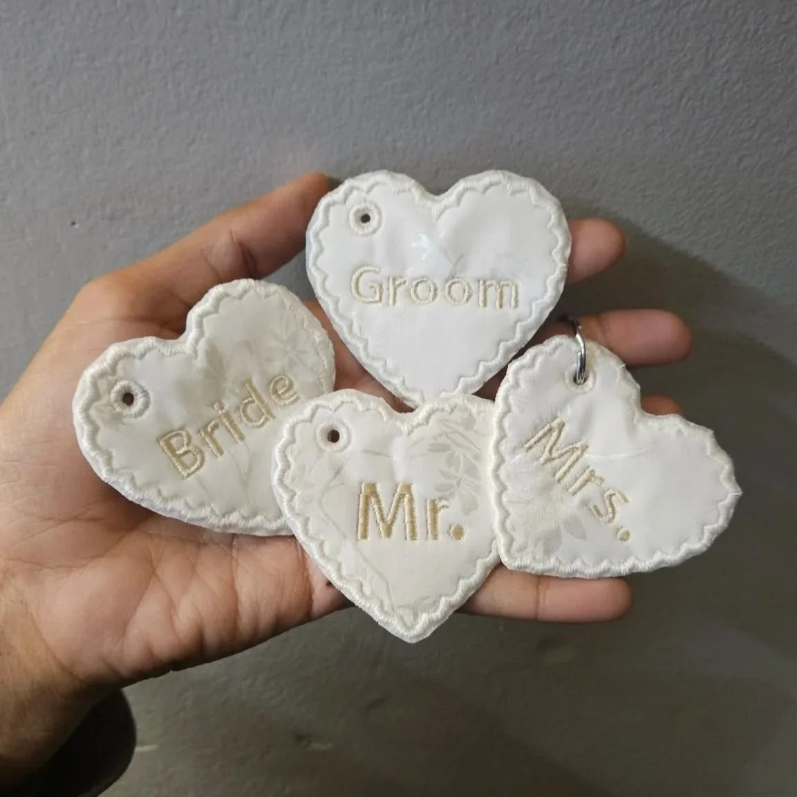 Personalized heart-shaped wedding charms with keychain holes, embroidered in rose gold thread, designed for brides, grooms, and wedding party keepsakes