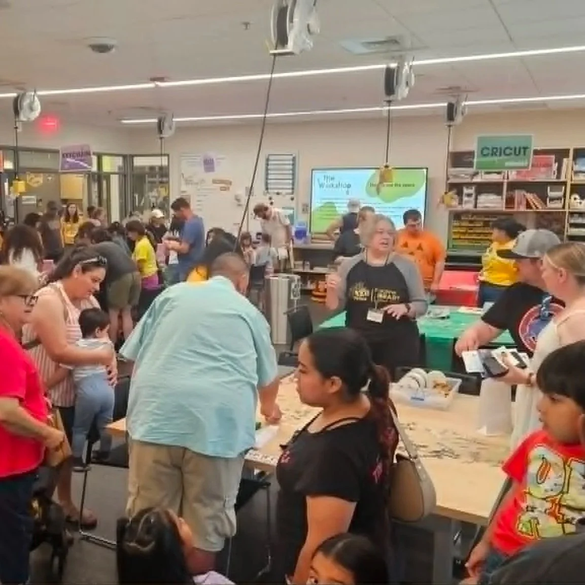 Large group of people of all ages doing different activities in a library makerspace