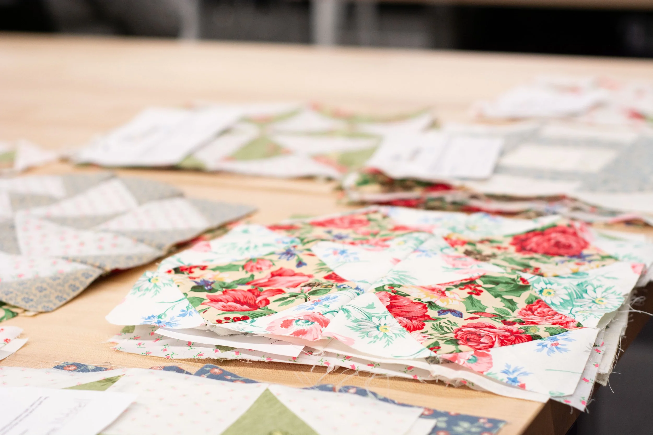 Various sheets of fabric with floral and patterned designs placed on a table.