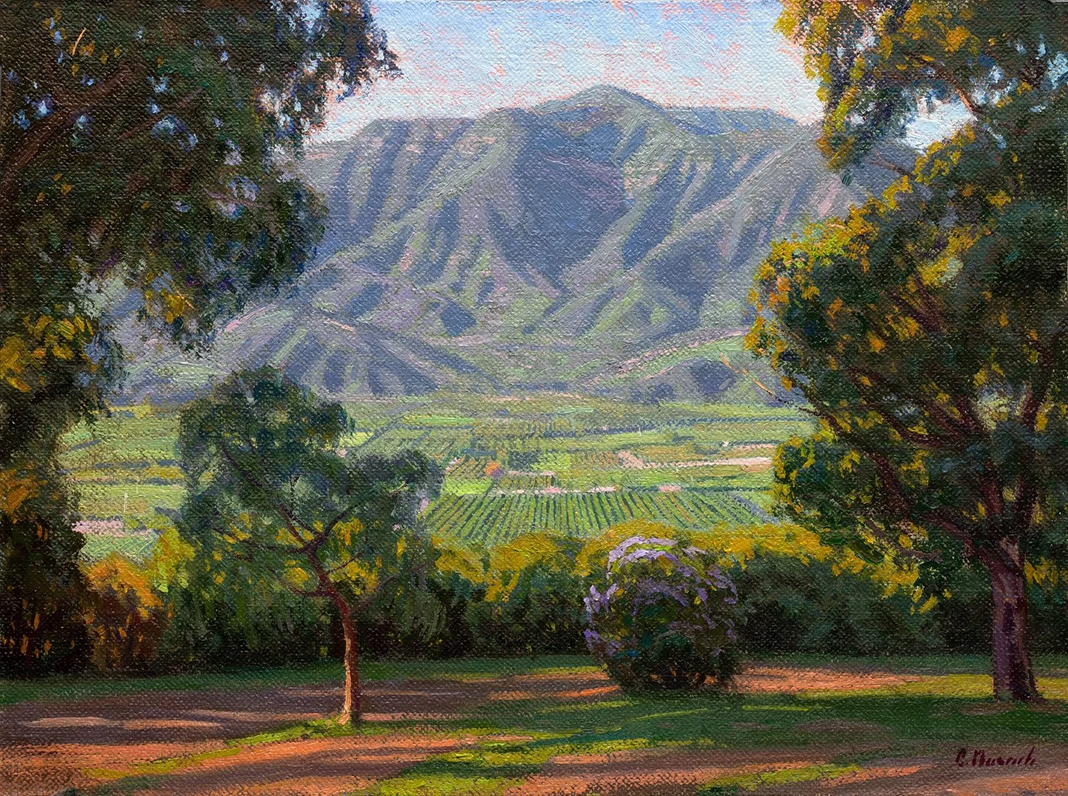 A landscape painting of a valley with trees in the foreground, green fields in the middle, and mountains in the background with a partly cloudy sky.