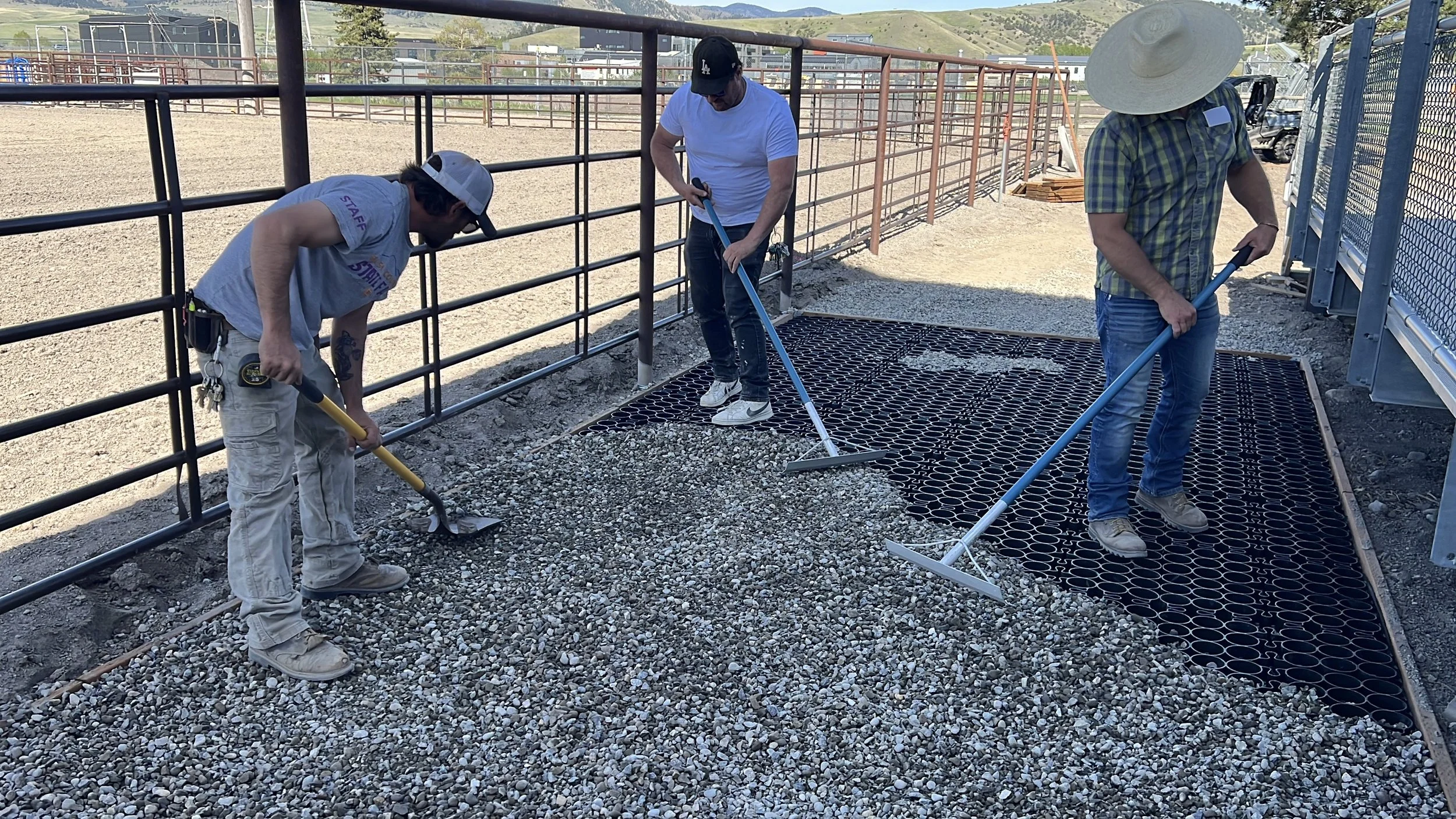 The crew follows the skid steer with rakes to evenly fill the cells