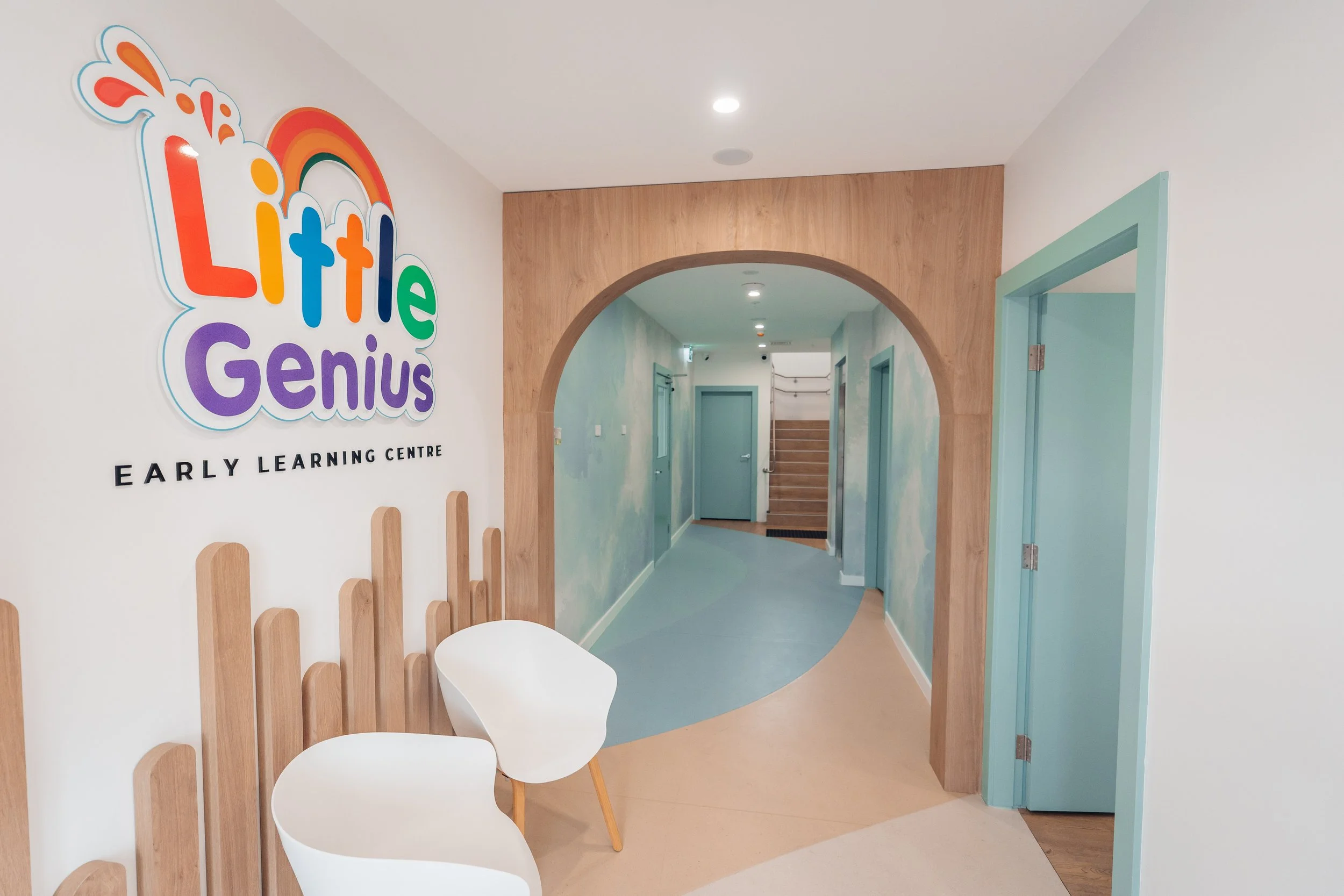 Interior of Little Genius Early Learning Centre with an arched doorway, colorful wall mural, and seating area with two white chairs.