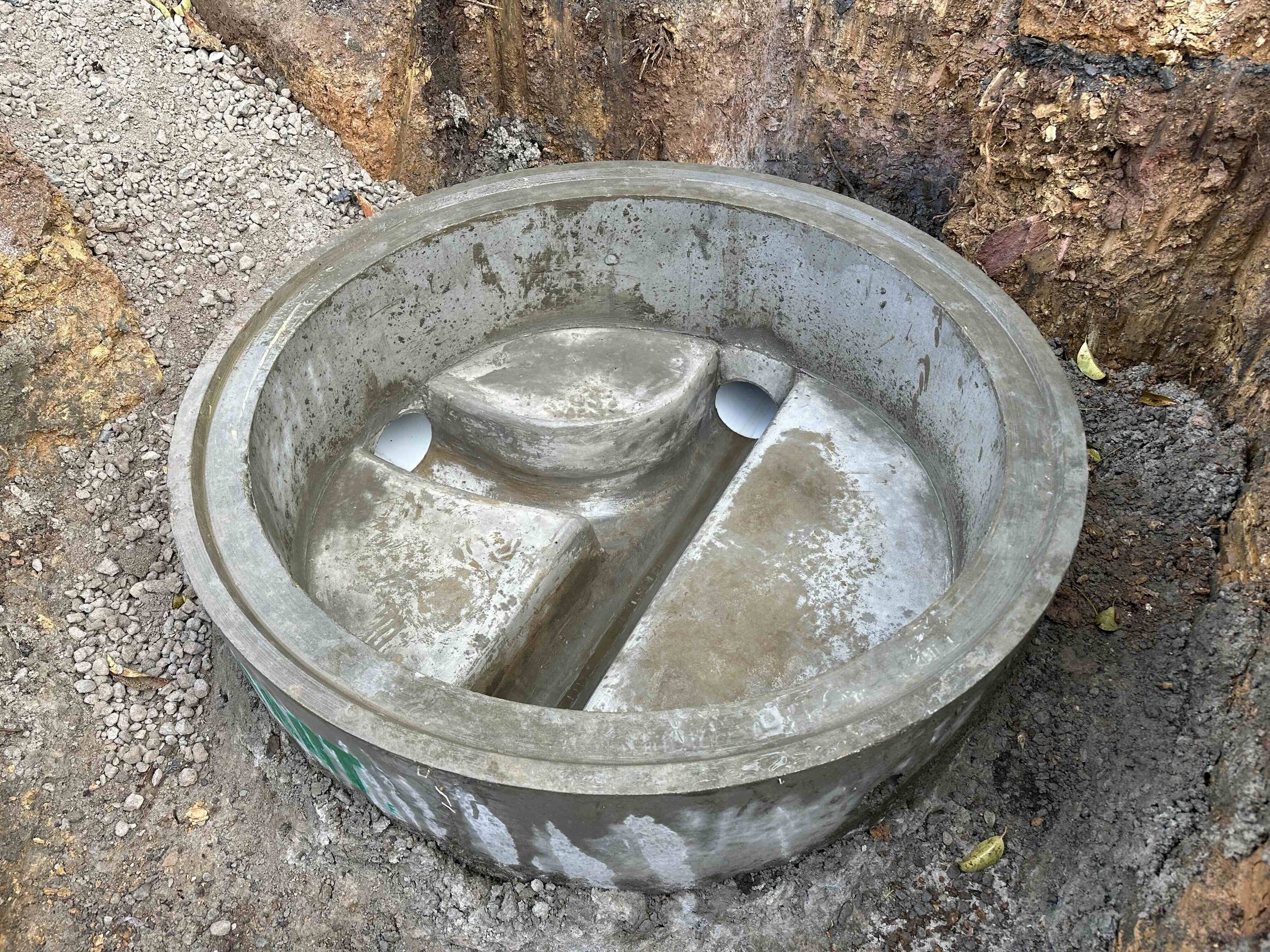 Metal utility vault lid removed and placed in a trench with dirt and soil around it.