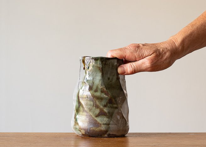Faceted vase with green brush marks, with hand for scale.jpg