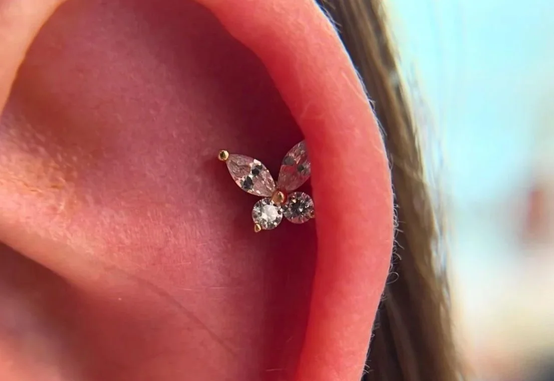 Close-up of a person's ear with a butterfly-shaped diamond cartilage piercing.
