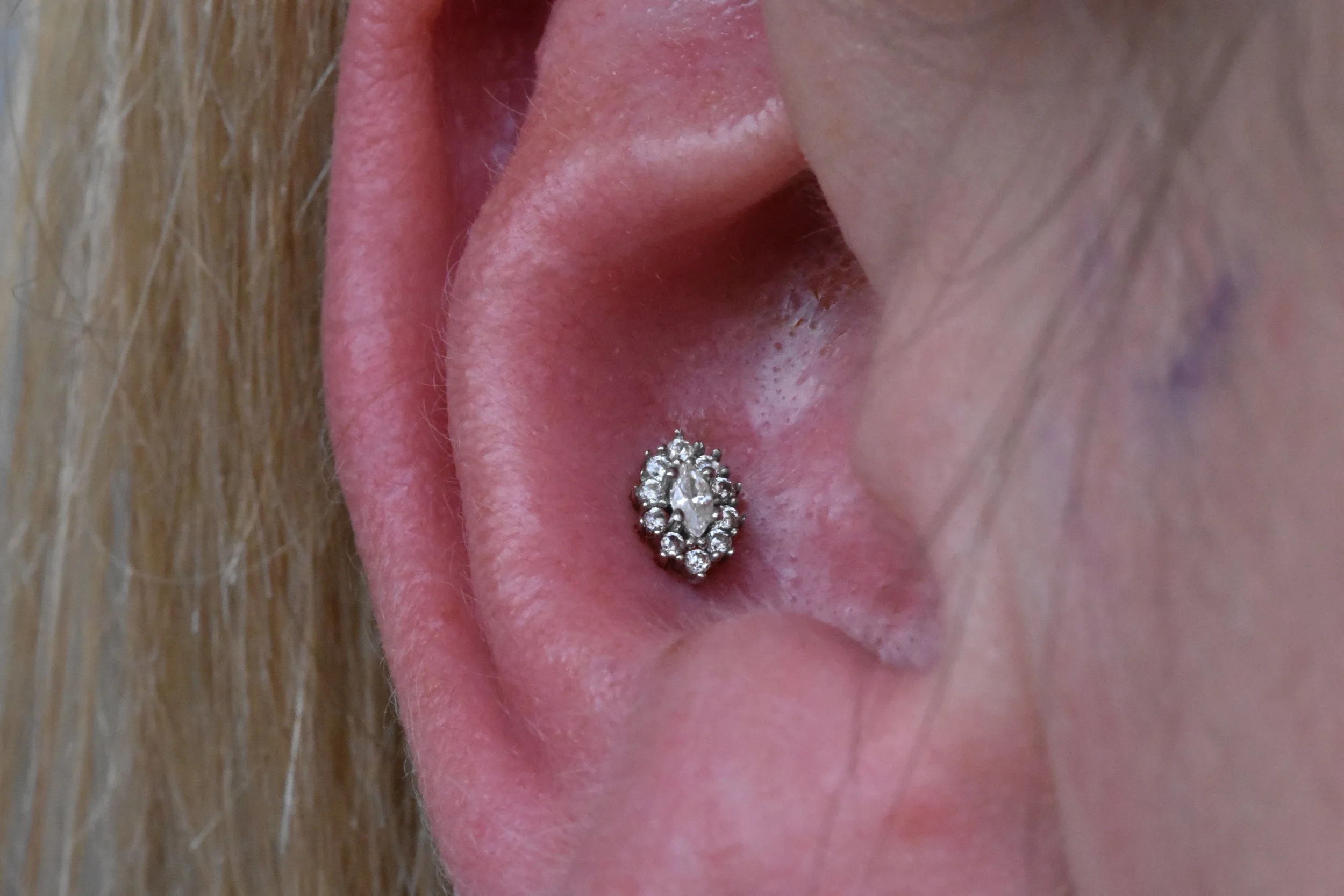 Close-up of a person's ear with a decorative stud earring filled with small diamonds or gems.