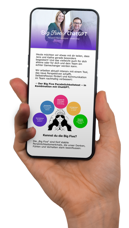 Smartphone in Hand zeigt eine Webseite über den Big Five Persönlichkeitstest mit Text und Diagrammen. Hintergrund unscharf, Fokus auf Bildschirm und Hand.