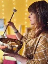 Femme jouant d'un bol chantant tibétain avec un maillet