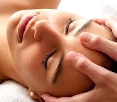 Personne recevant un massage facial, mains sur le front.