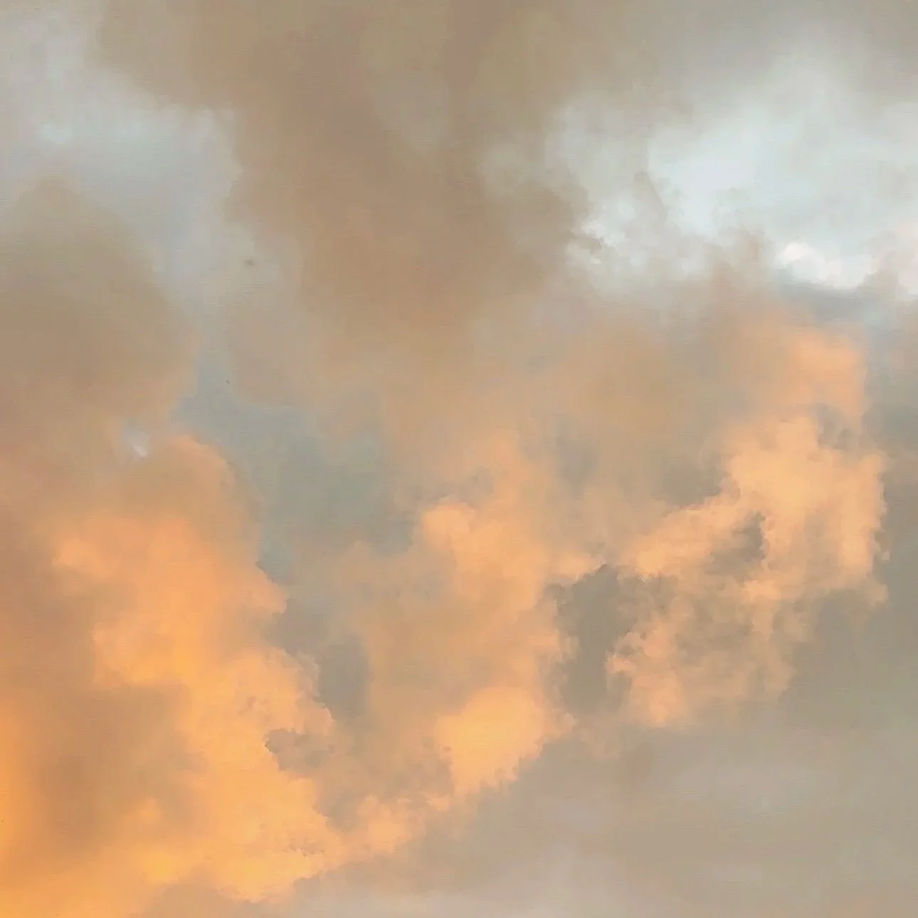 A sky with clouds illuminated by the setting or rising sun, showing orange, pink, and blue hues.