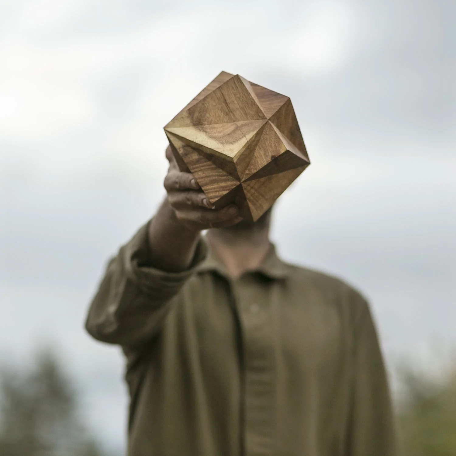 Man holding up an intricate wooden sculpture