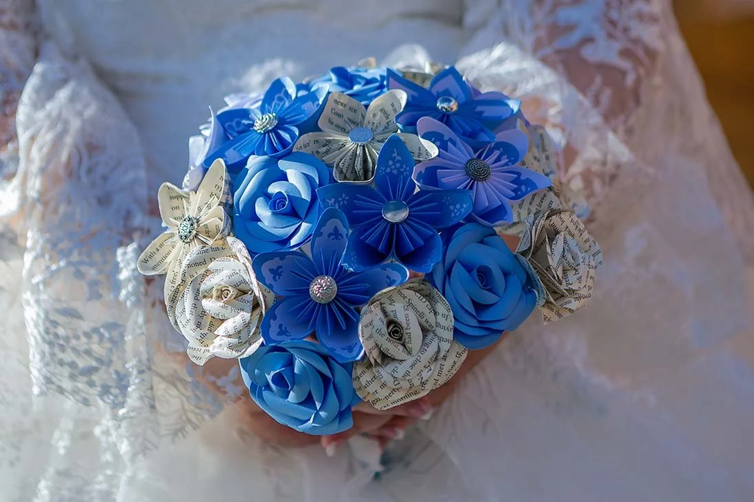 A vibrant blue wedding bouquet made up of artistic paper flowers, highlighting a unique and creative floral design captured by borcila dorinel photography, last minute documentary wedding photographer in northampton.