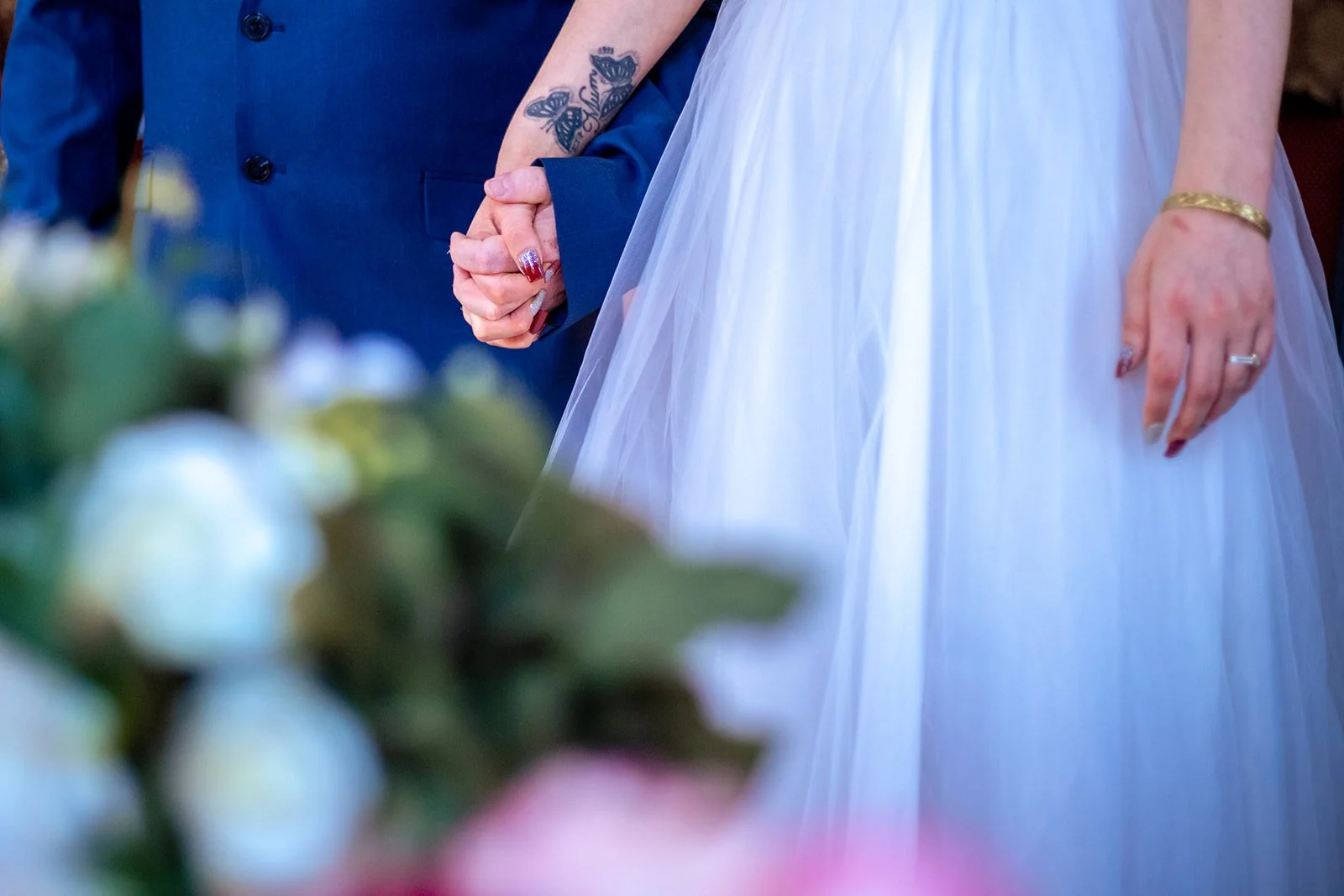 Bride and groom wedding portrait with flowers on the foreground.