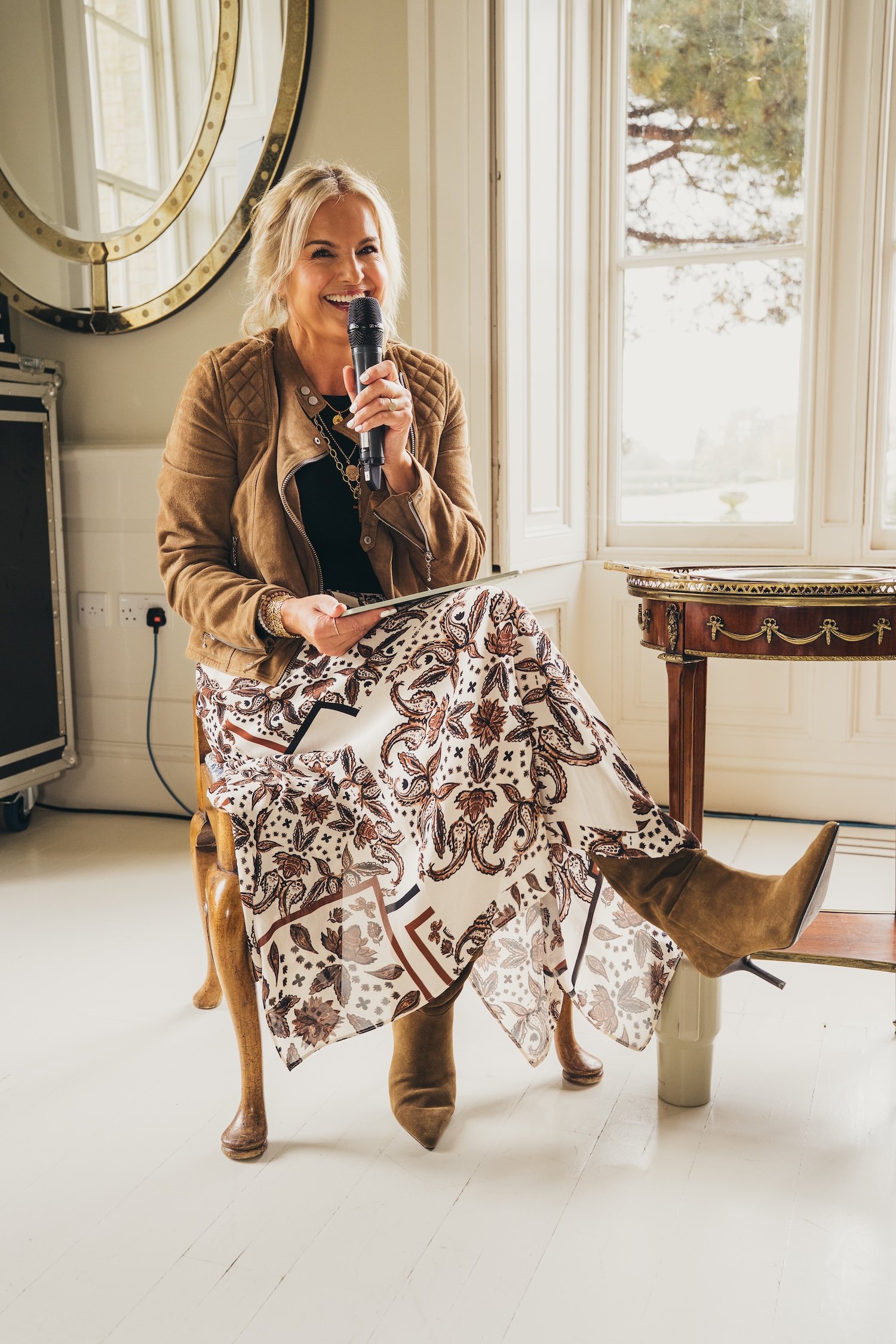 Katy Hill smiling, holding a microphone  at a She's Electric event with Motorfinity