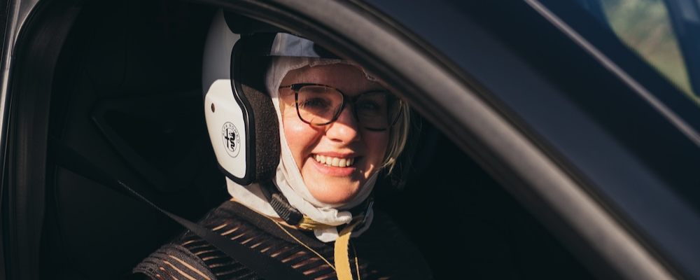 Rebecca Day smiling wearing a crash helmet in an Alfa Romeo