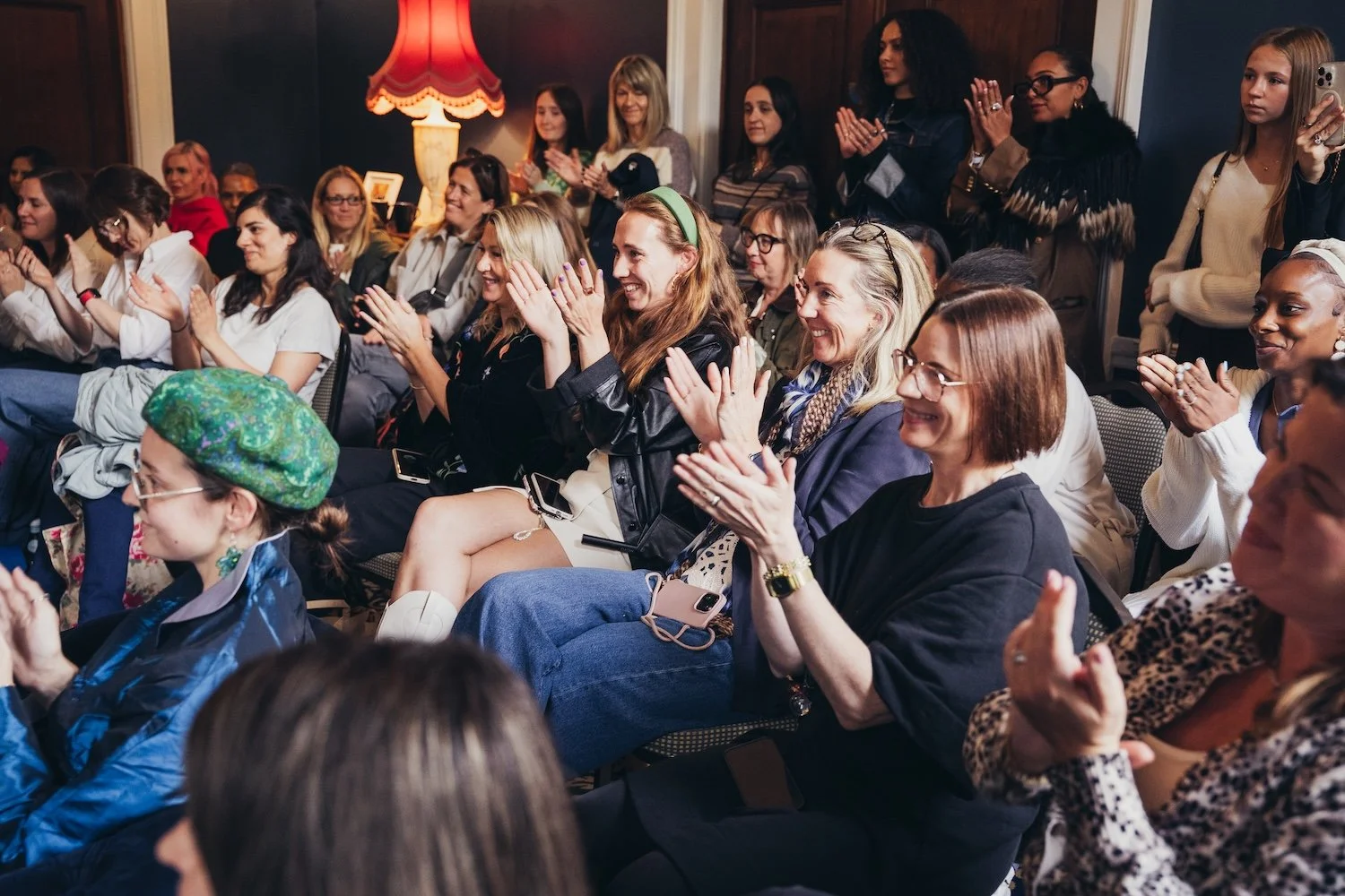 A group of women an girls sitting and standing in an audience, smiling and clapping during an she's electric event with polestar