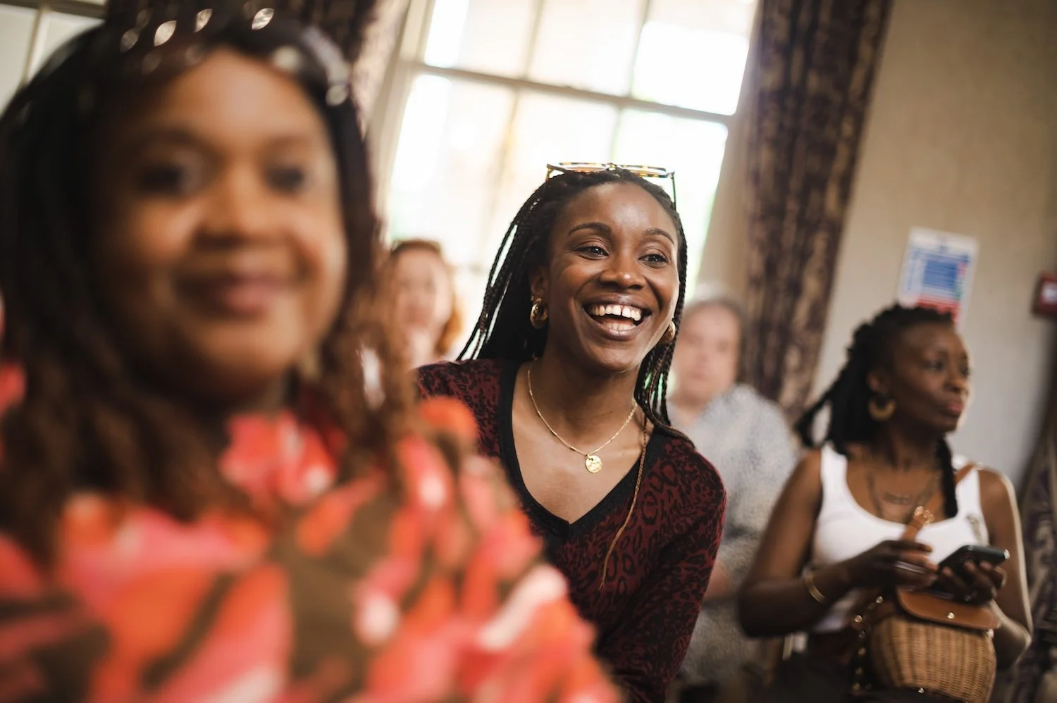 A group of women sitting indoors at a She's Electric event with Tesla, smiling and engaging with each other.