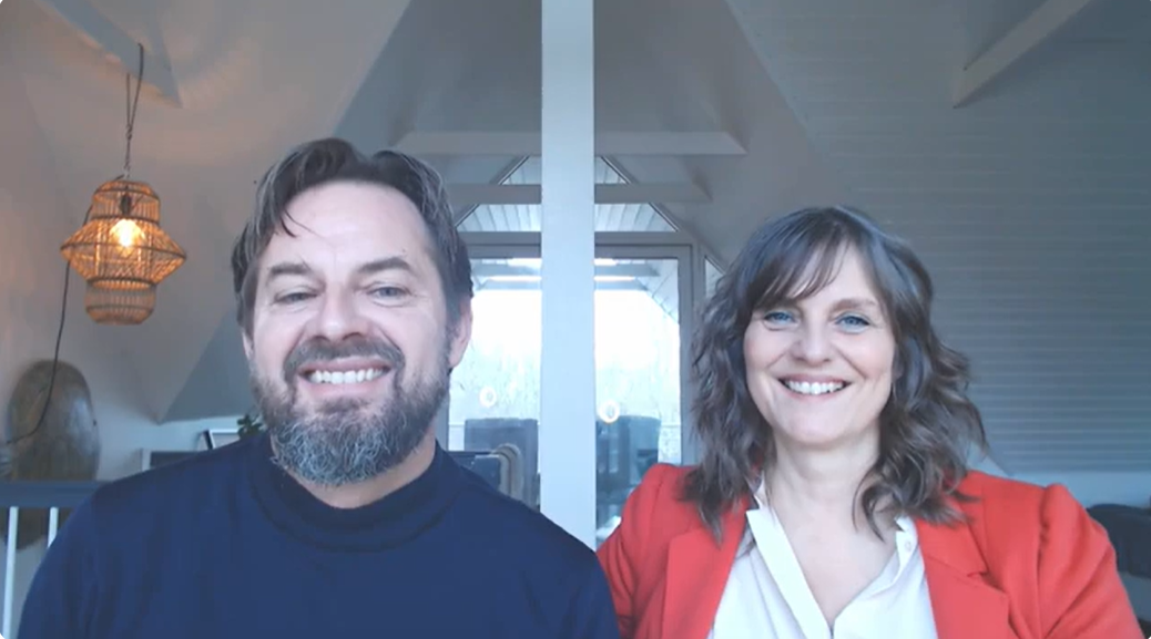 En mand og en kvinde smiler foran et vindue i et lyst værelse.