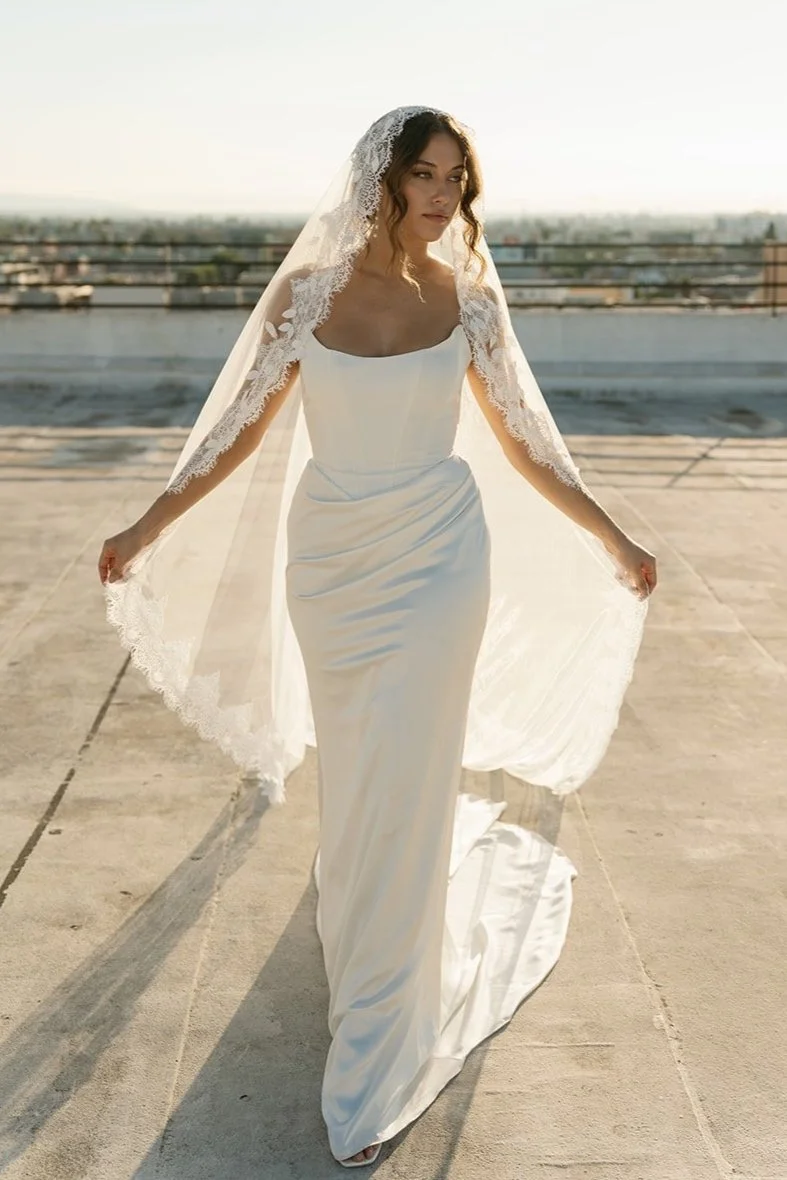 bride wearing simple fitted wedding dress with cathedral lace veil