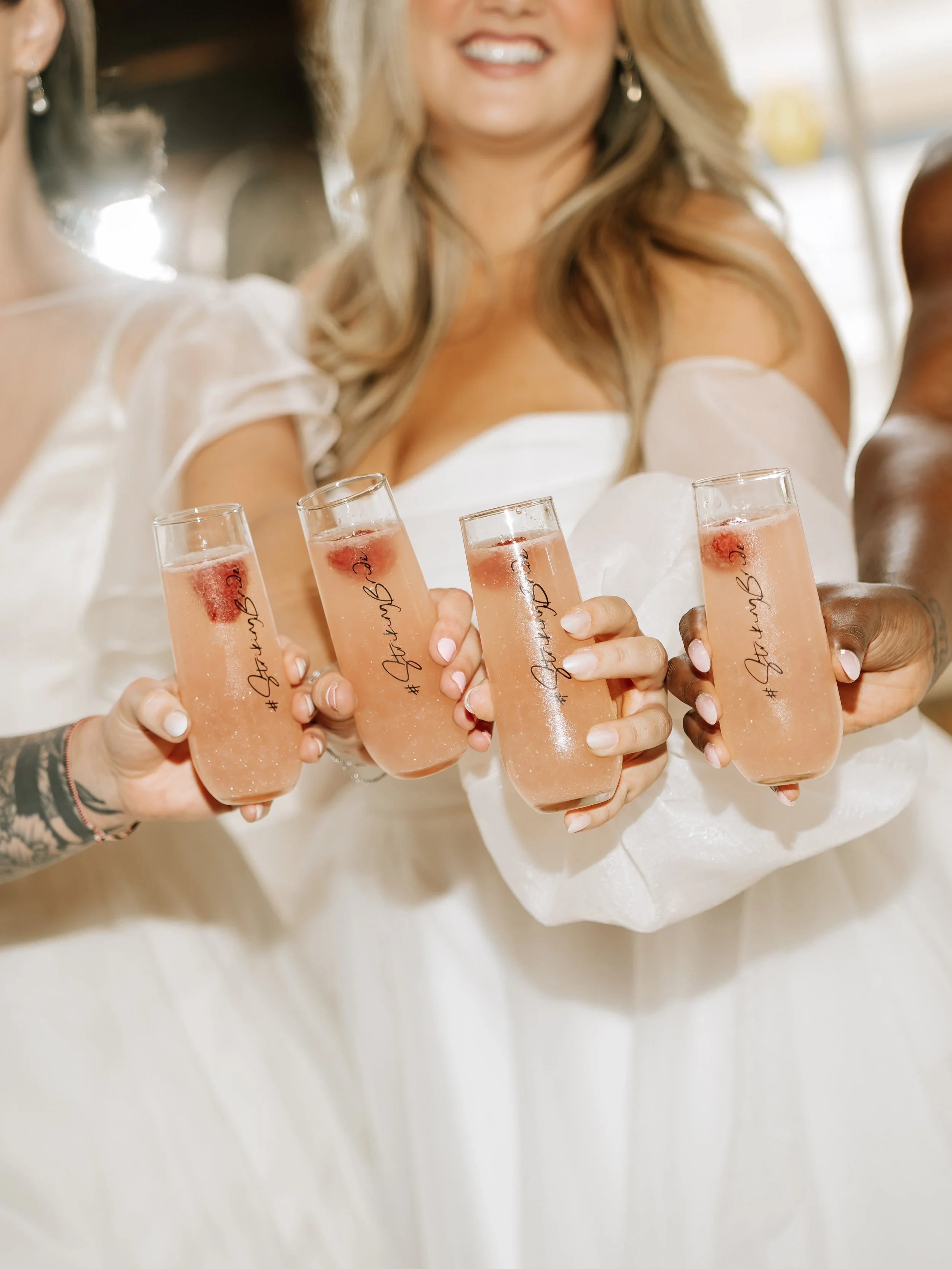 four brides clinking champagne flutes together in celebration during a bridal appointment
