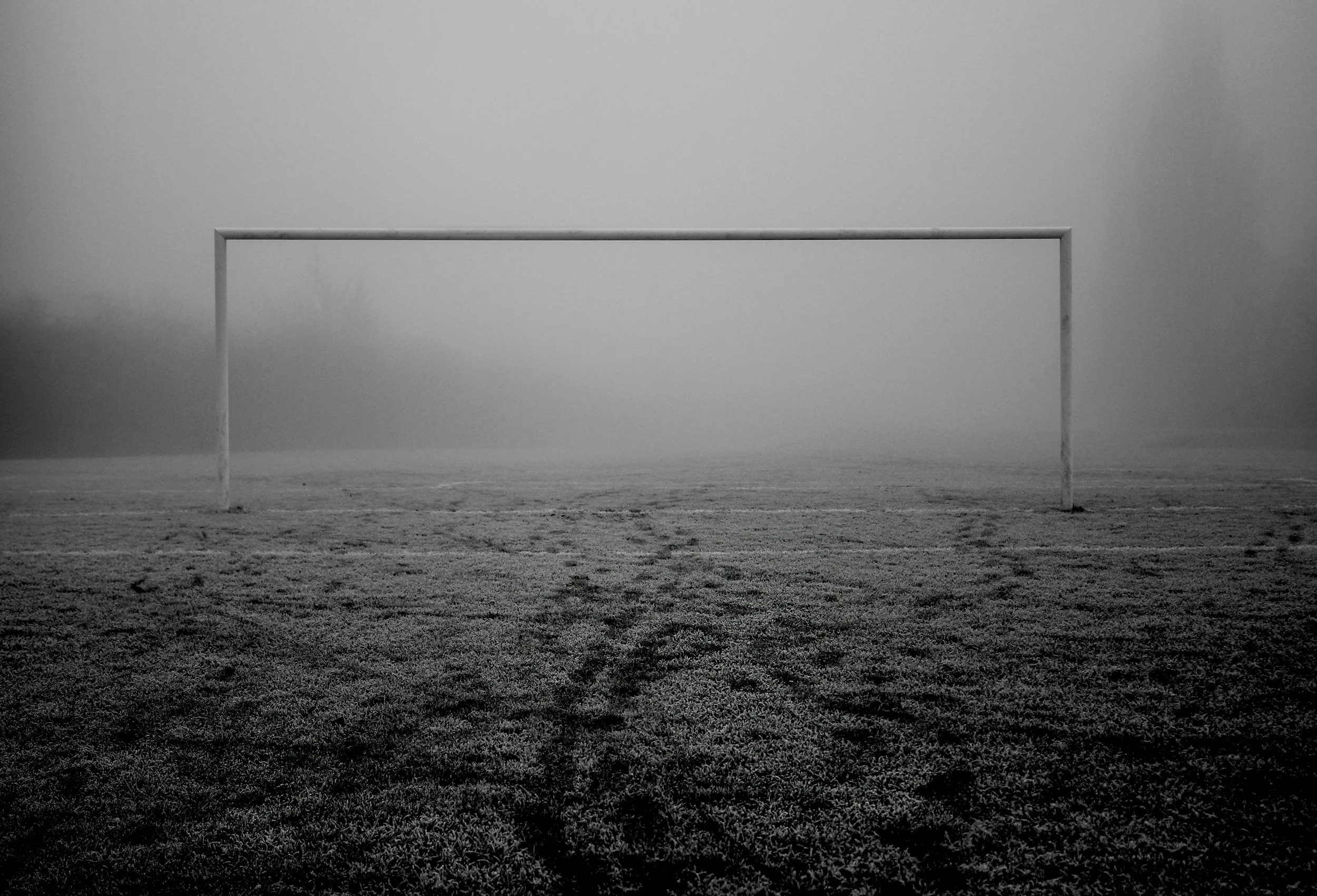 A dark, moody black-and-white photo of a goalpost symbolizes the anxious feeling of chasing unreachable standards caused by perfectionism and OCD