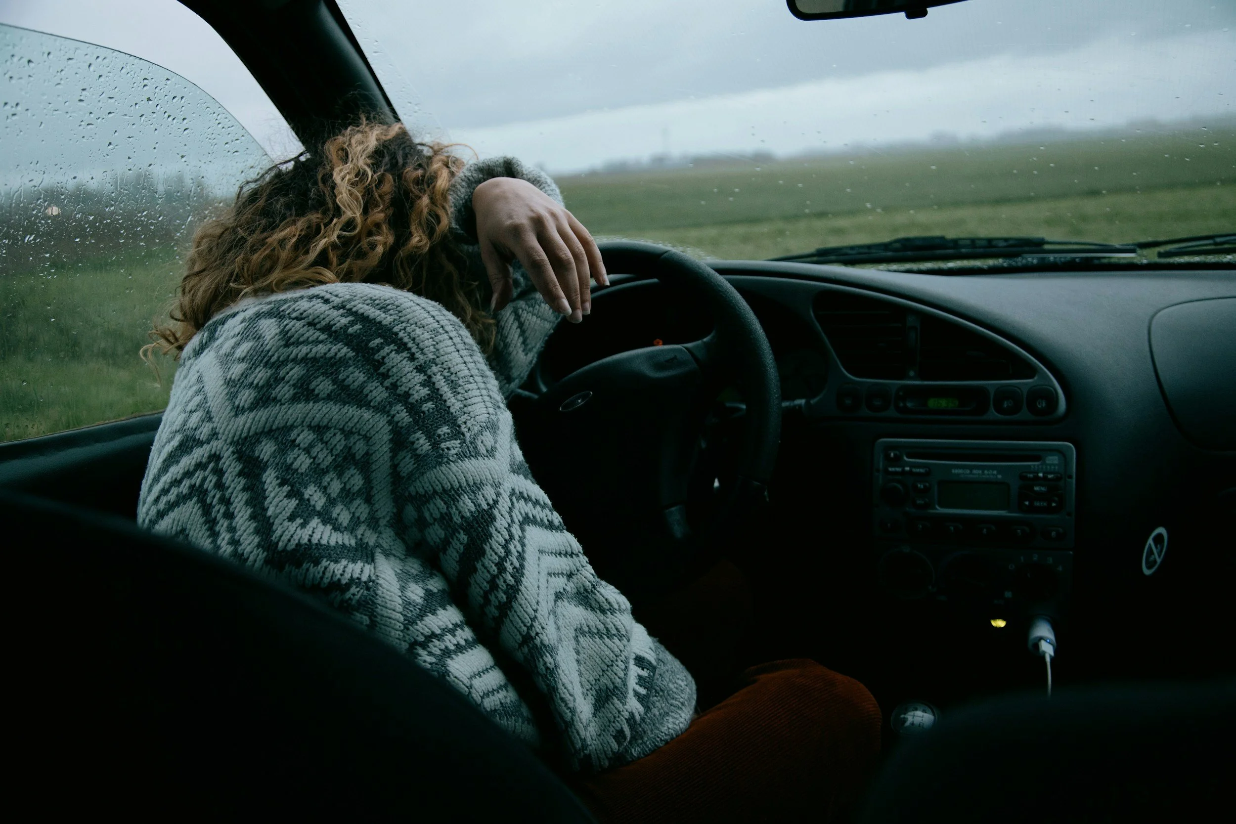 Woman overwhelmed in her car on a rainy day, capturing the emotional first wave of OCD recovery—facing fear, doubt, and the hard work of learning that fear isn’t truth.