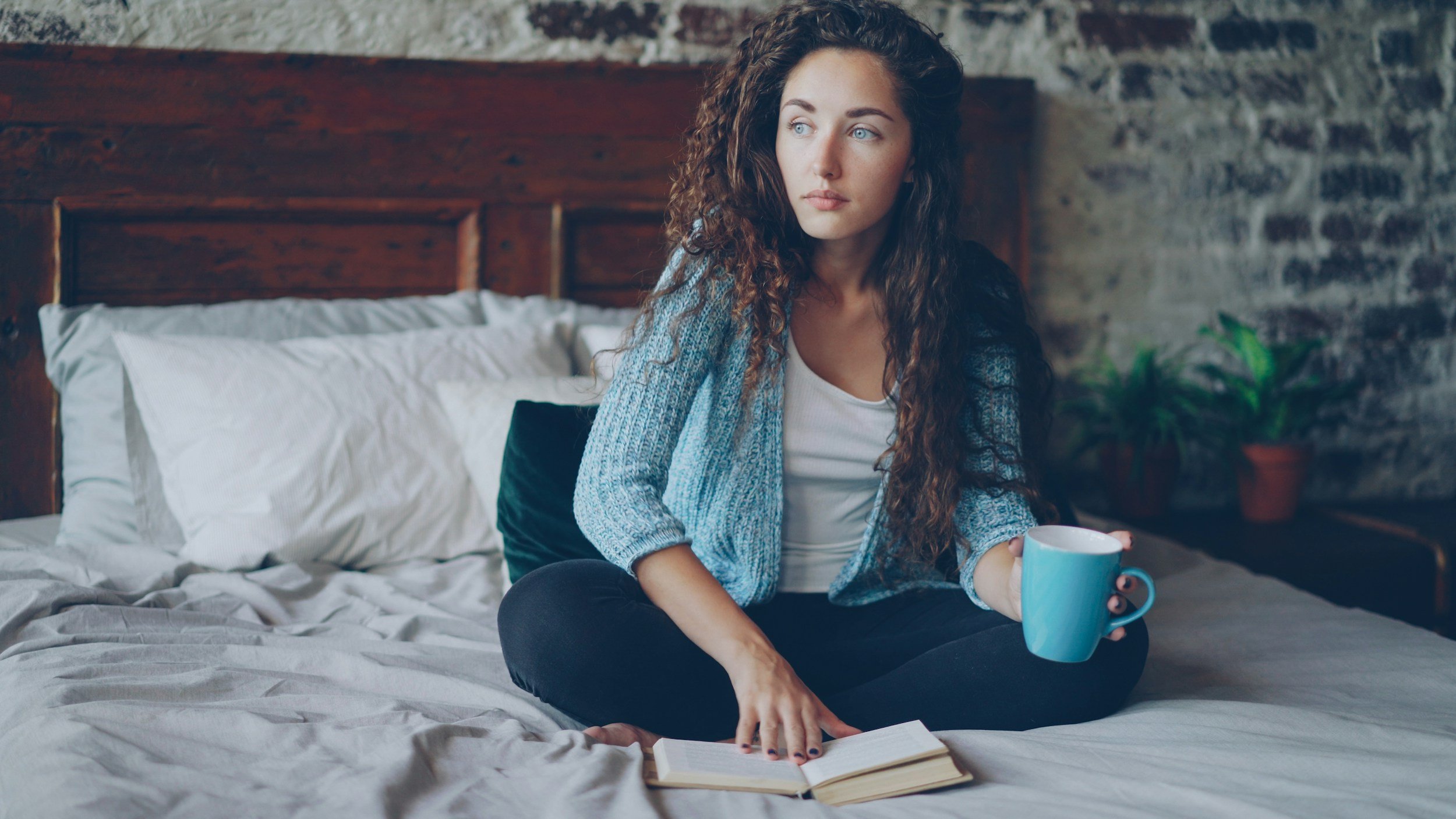 Woman sitting on her bed with a journal and coffee, looking peaceful and reflective, symbolizing the first real breakthrough in OCD recovery when the mind finally feels quieter and more her own.