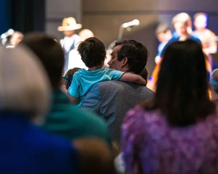 A father holds his son so he can see the platform and musicians on Sunday during worship at West End Community Church in Nashville, TN