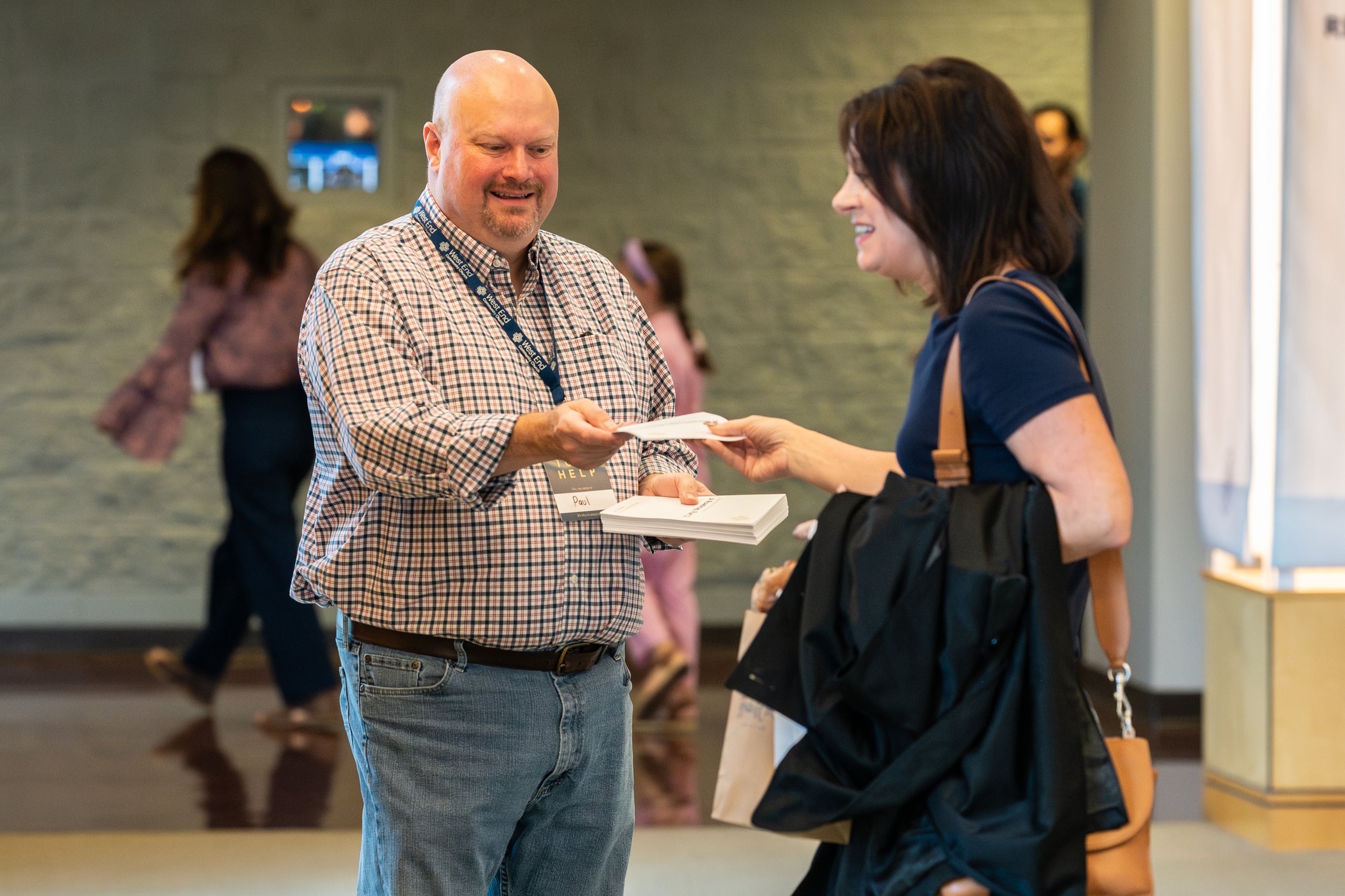 Smiling volunteer greeting and handing out Sunday worship bulletins